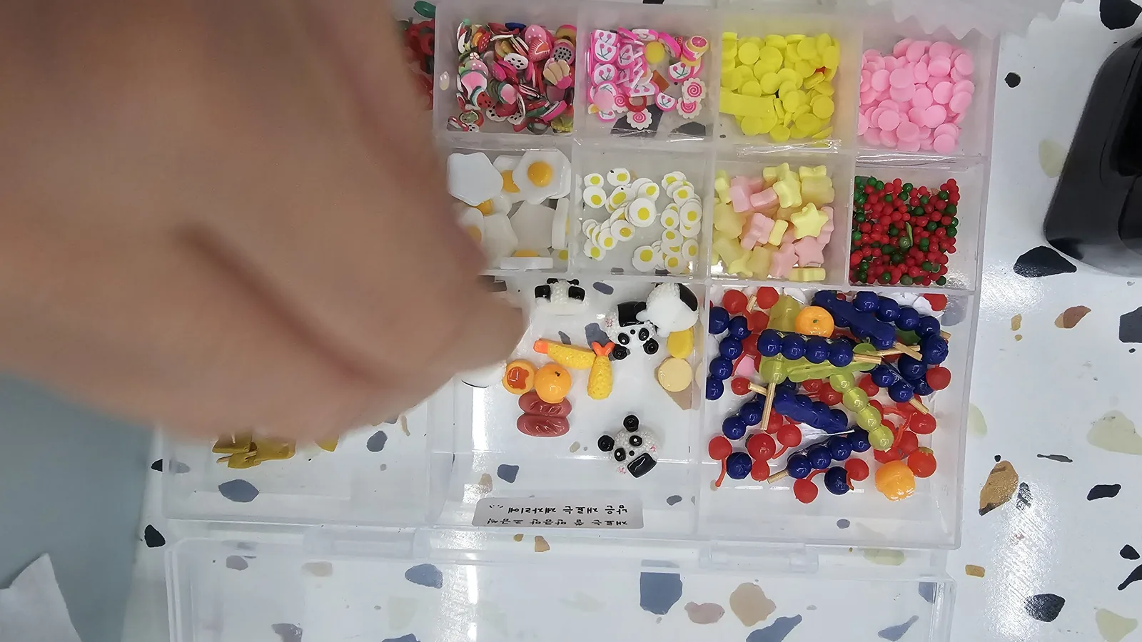 Close-up of a miniature ingredient box containing tiny egg, bear jelly candy, vegetables, and panda onigiri decorations