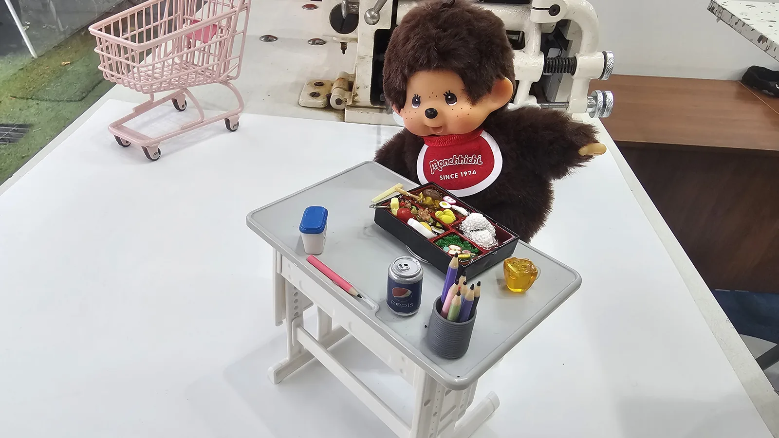 Completed lunchbox keyring posed with Monkichi plush toy and mini desk set, leather sewing machine visible in background