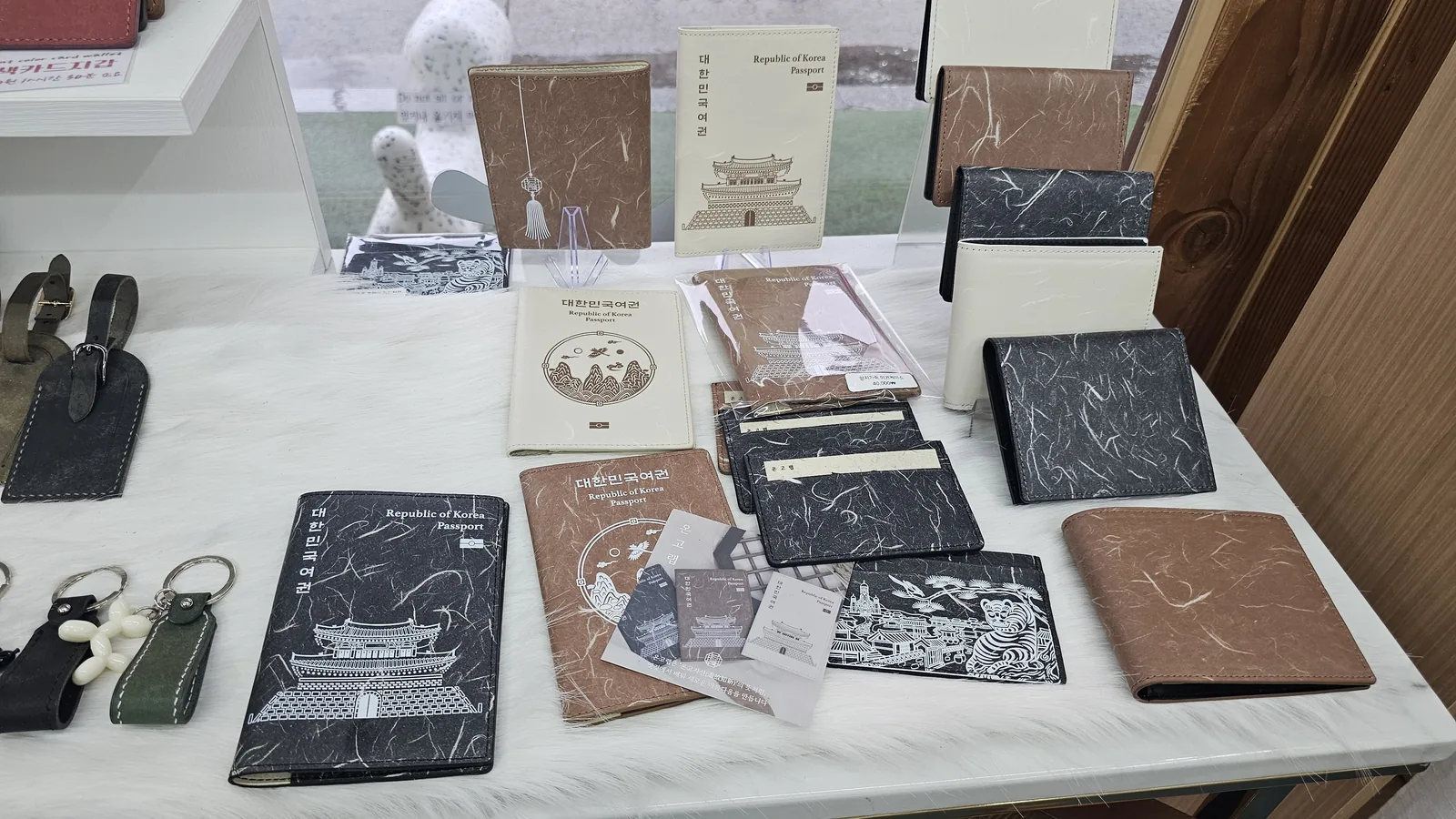 Leather goods display at Amado featuring Korean passport holders, card wallets, and name tag keychains