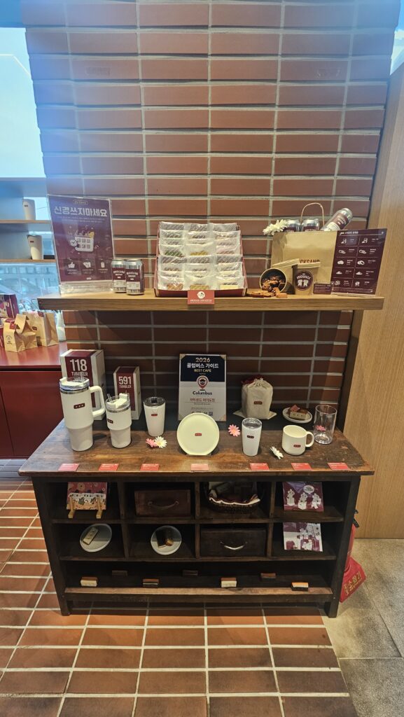 Bricksand merchandise display featuring logo tumblers and mugs on brick tile wall background in Yeouido