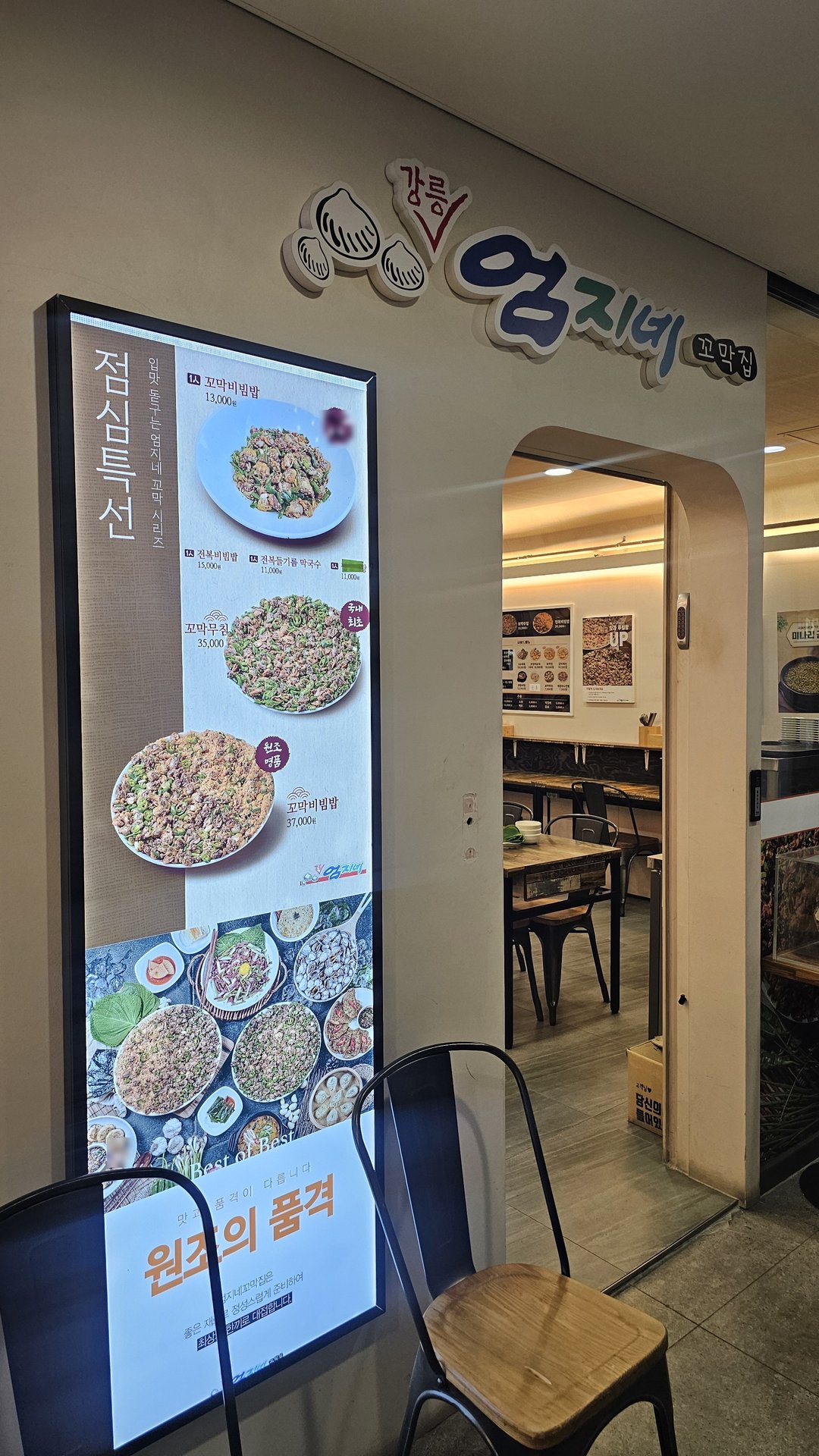Entrance of Eomjine Kkomak House in Yeouido with illuminated menu board showing cockle dishes