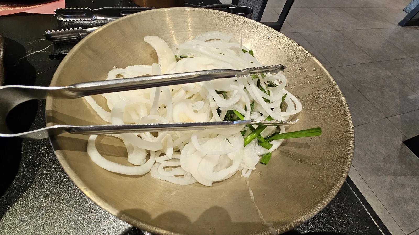 Sliced onions and scallions in stainless bowl, accompaniment for Korean BBQ at Galbidorak