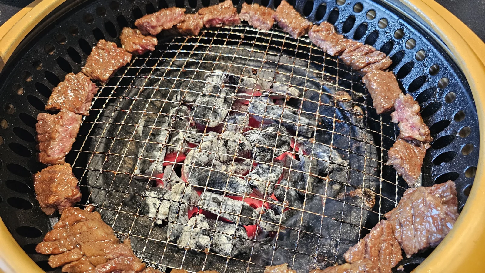 Small pieces of marinated beef arranged along charcoal grill edge at Galbidorak