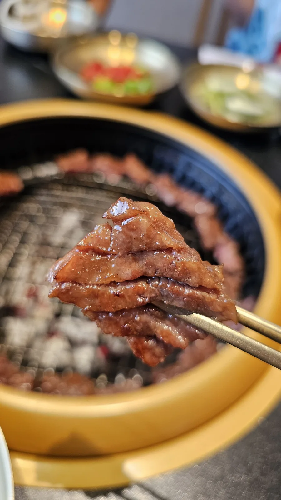 Close-up of juicy cooked marinated beef held by tongs at Galbidorak Korean BBQ
