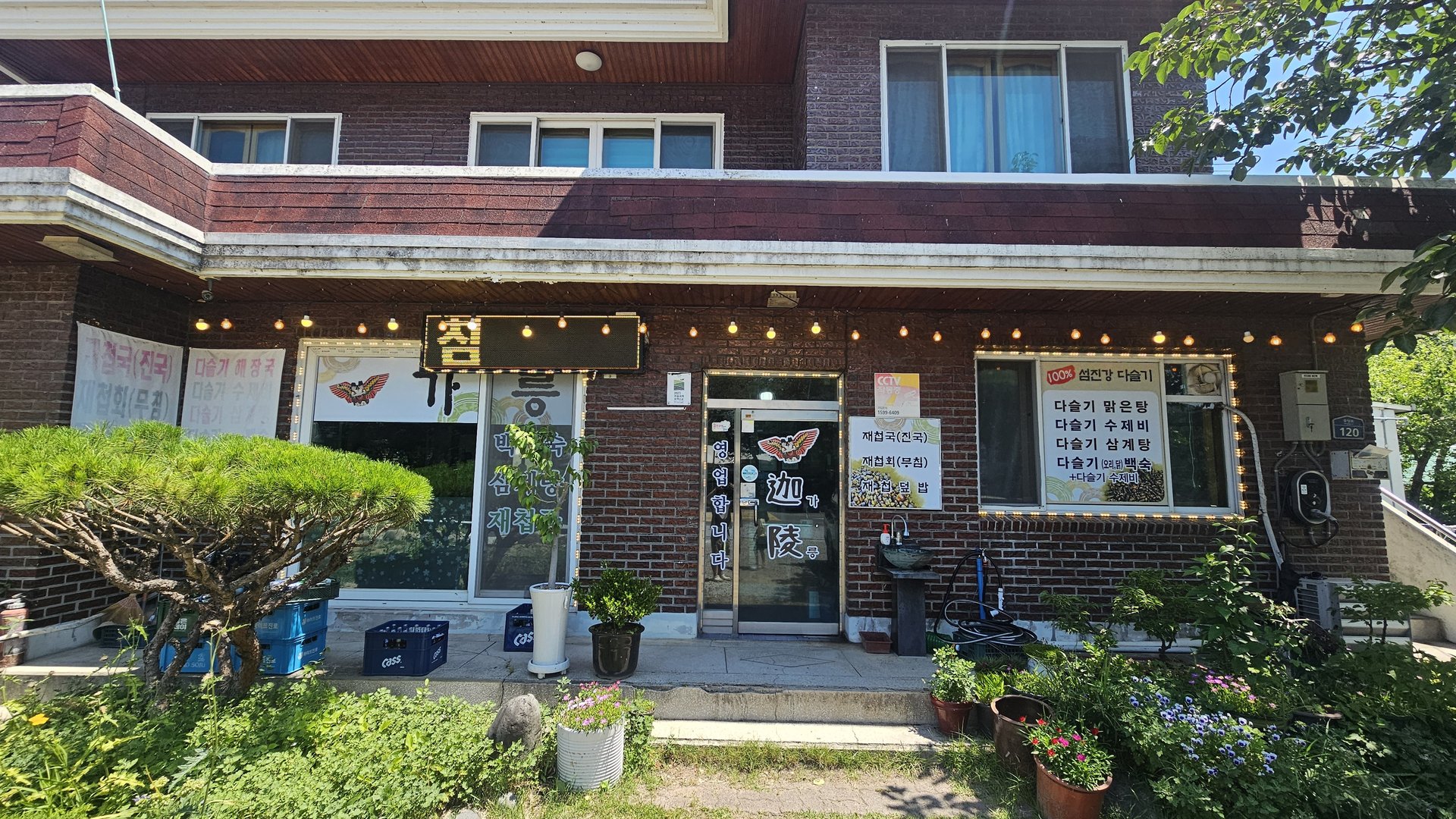 Side exterior of Gareung Sikdang Hadong with illuminated sign and daseulgi freshwater snail banner in daytime