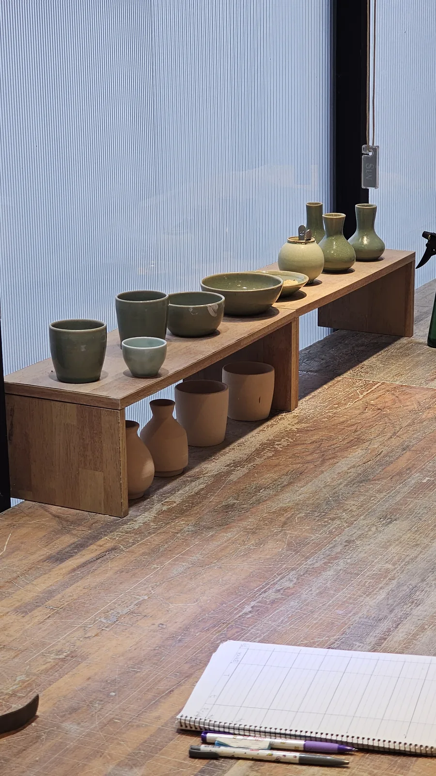 Display shelf with celadon-blue cups, bowls, and vases for sale at Udoye Gongbang Jeonju