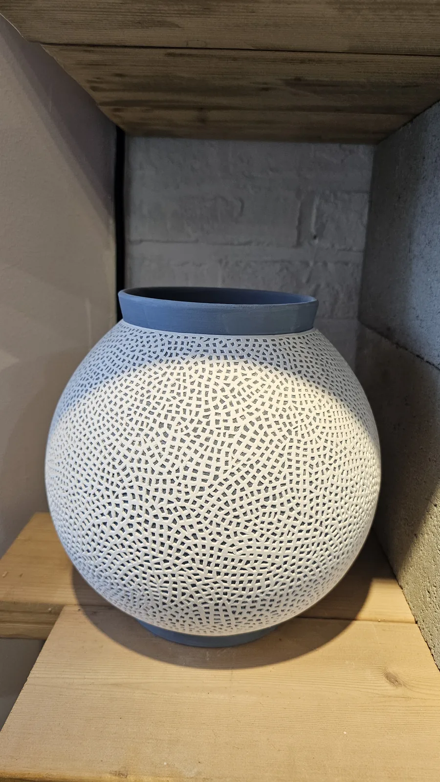 Close-up of a round white porcelain jar with intricate carved lattice pattern at Udoye Gongbang Jeonju