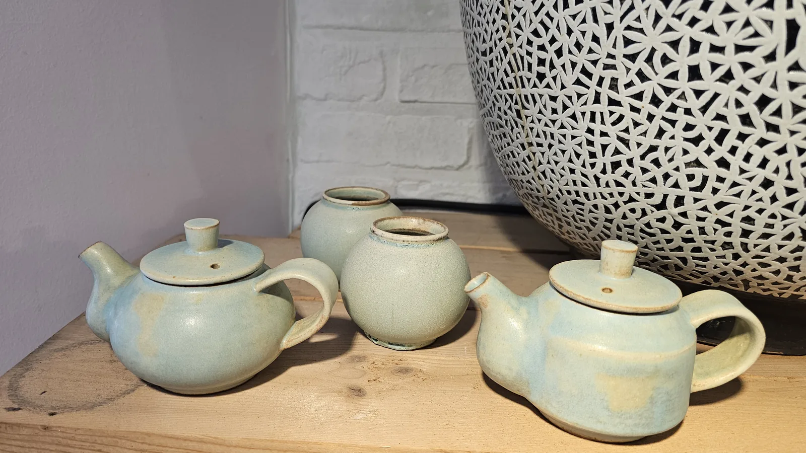 Two celadon teapots and two celadon jars on a wooden display shelf at Udoye Gongbang