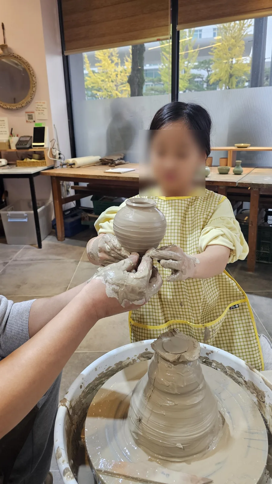 Young girl holding her completed round ceramic jar with both hands at Udoye Gongbang Jeonju