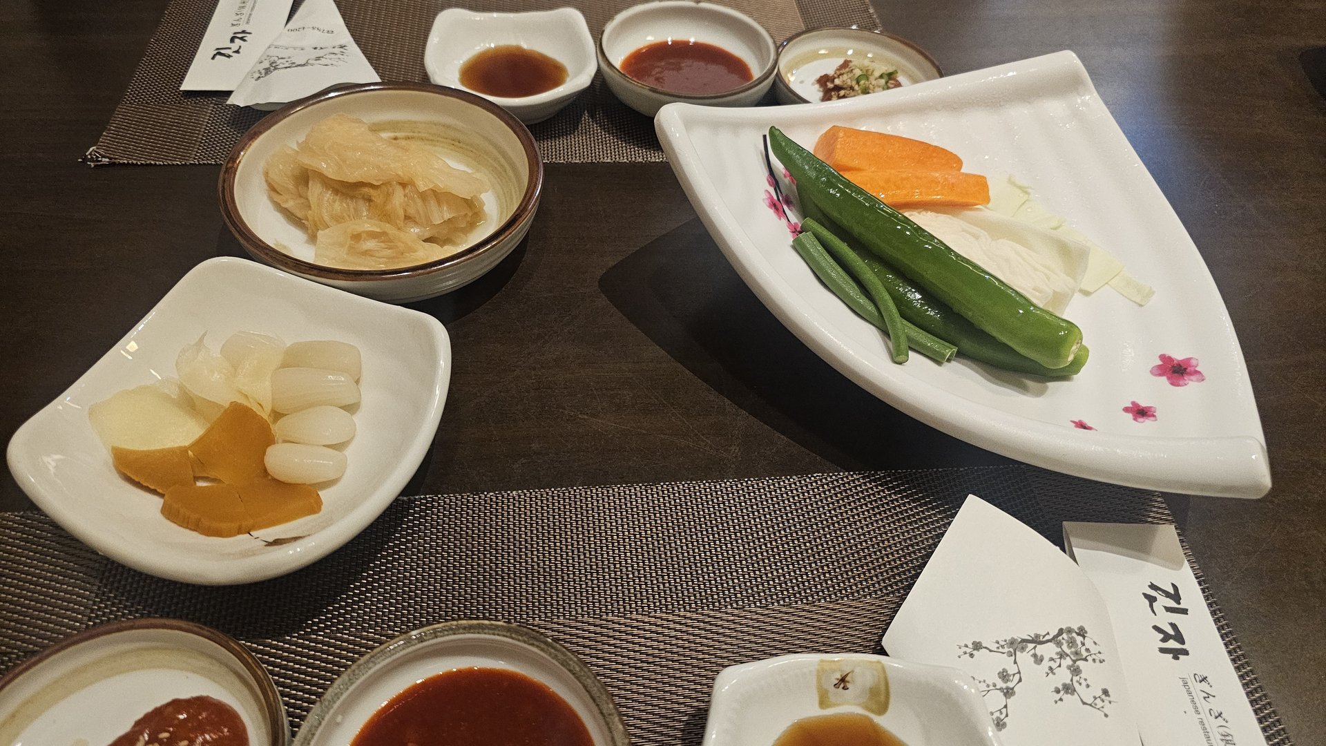 Appetizer tray with pickled radish, fresh vegetables, and four sauce cups at Ginza Yeouido
