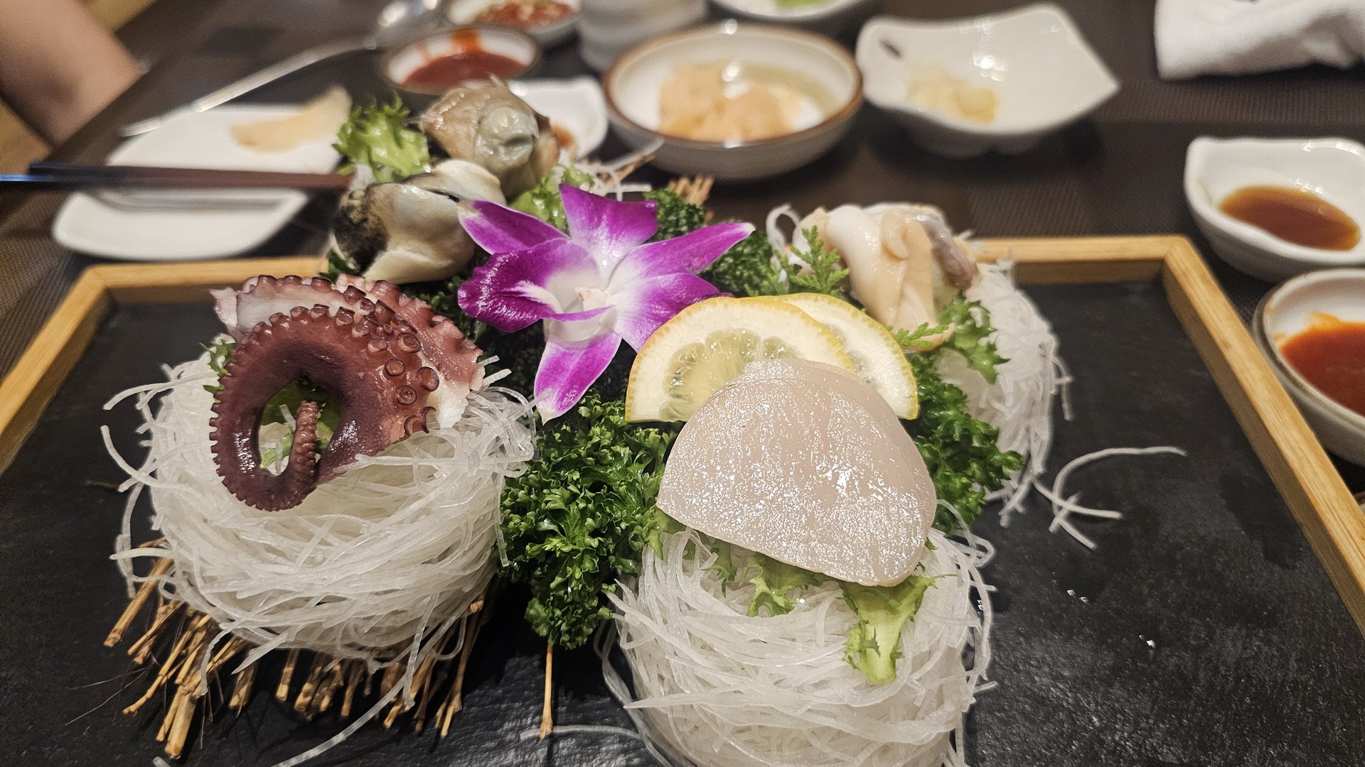 Seafood assortment of octopus, scallop, and oyster on straw tray with sea urchin garnish at Ginza Yeouido