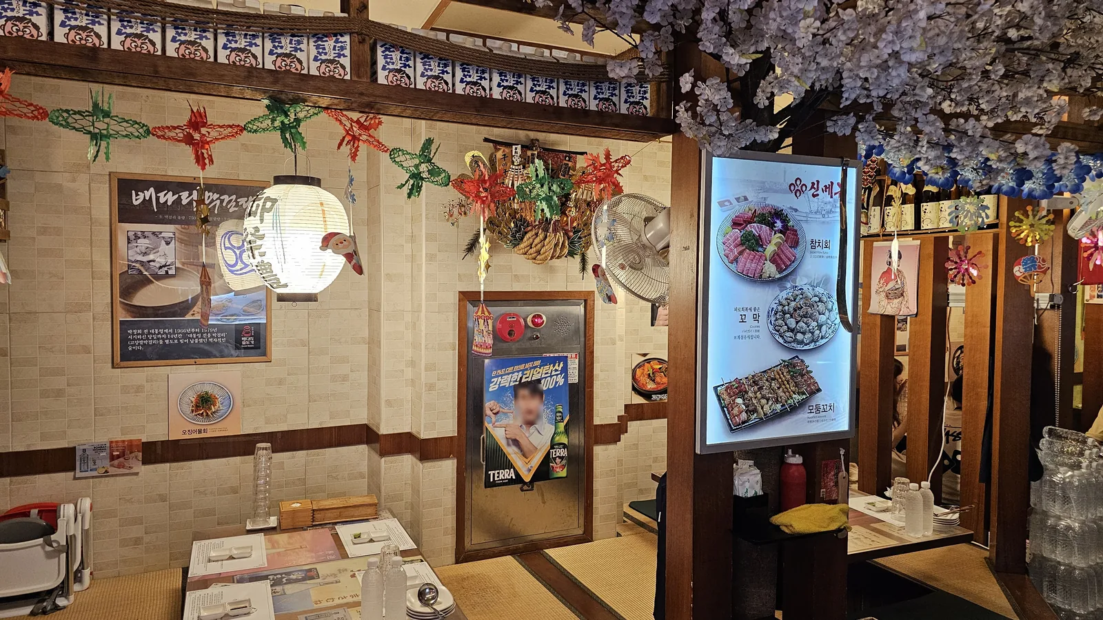Interior wall of Guigui Yeouido decorated with cherry blossom branches, paper lanterns, and retro TUNA advertising poster