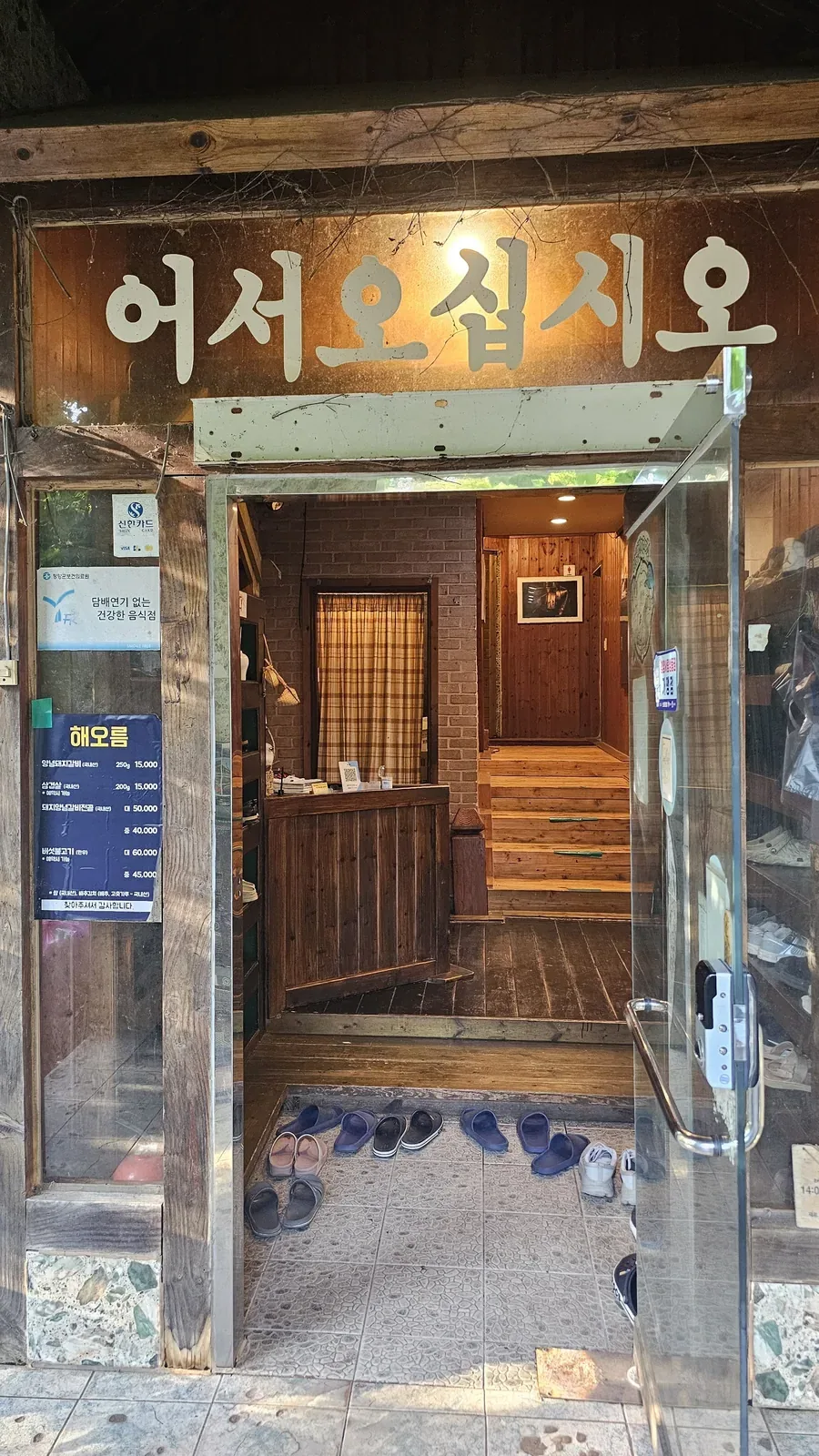 Wooden entrance and sign of Haeoeum restaurant with slippers visible at the door