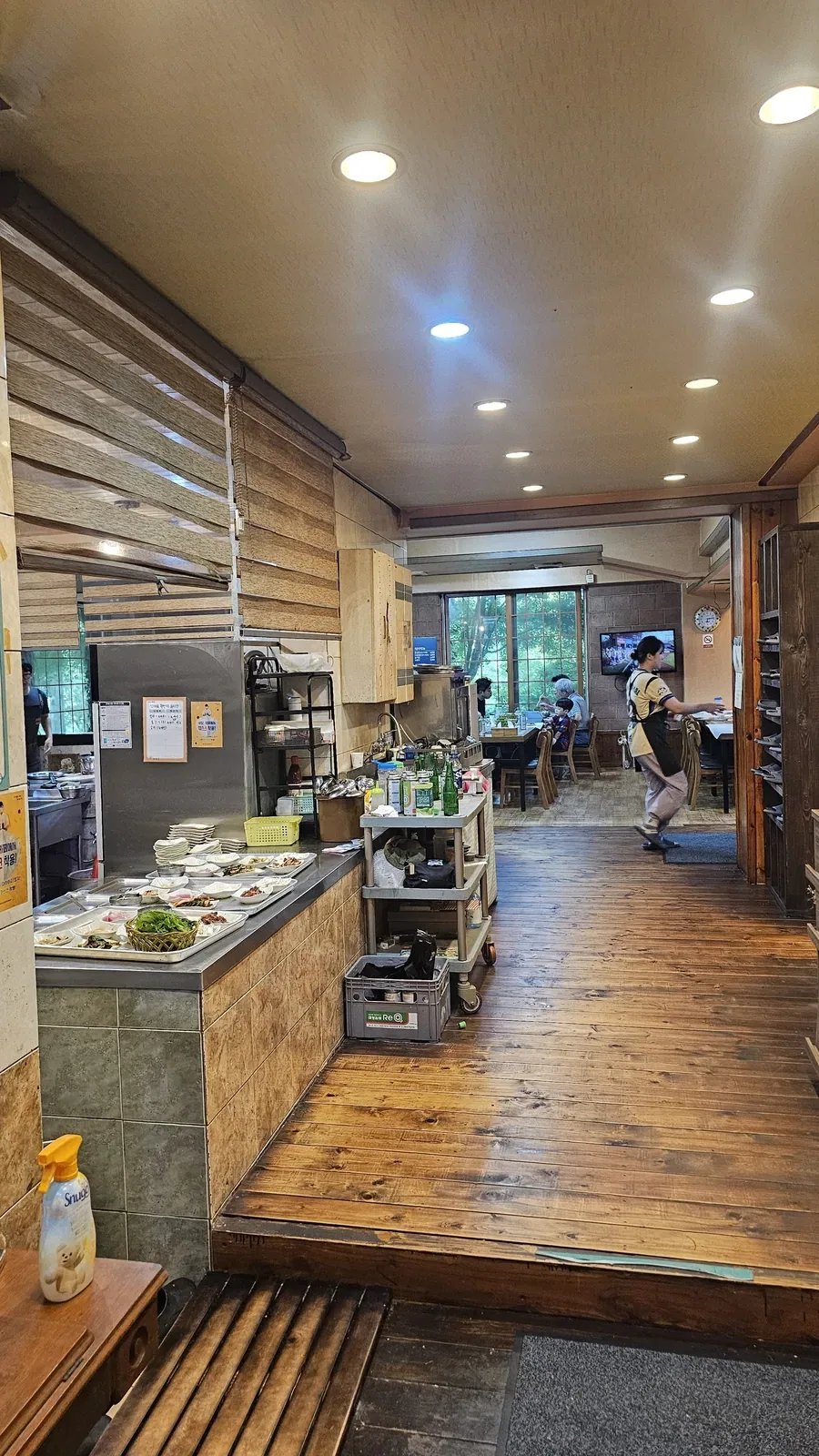 Warm wooden interior of Haeoeum restaurant with customers dining and open kitchen counter