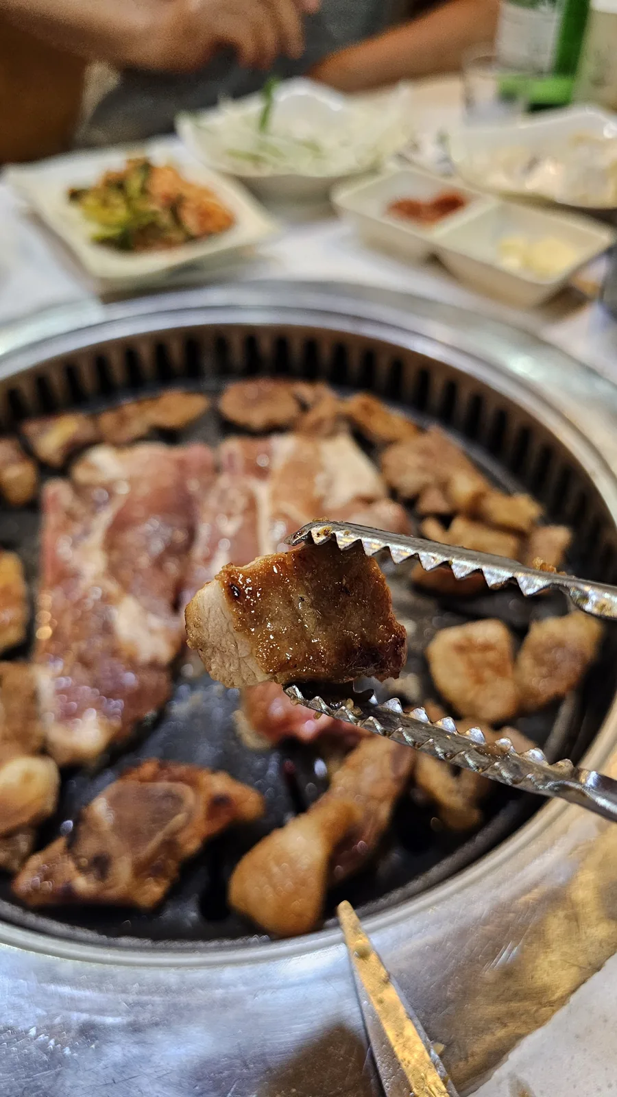 Perfectly cooked yangnyeom galbi piece being lifted with tongs at Haeoeum Cheongyang