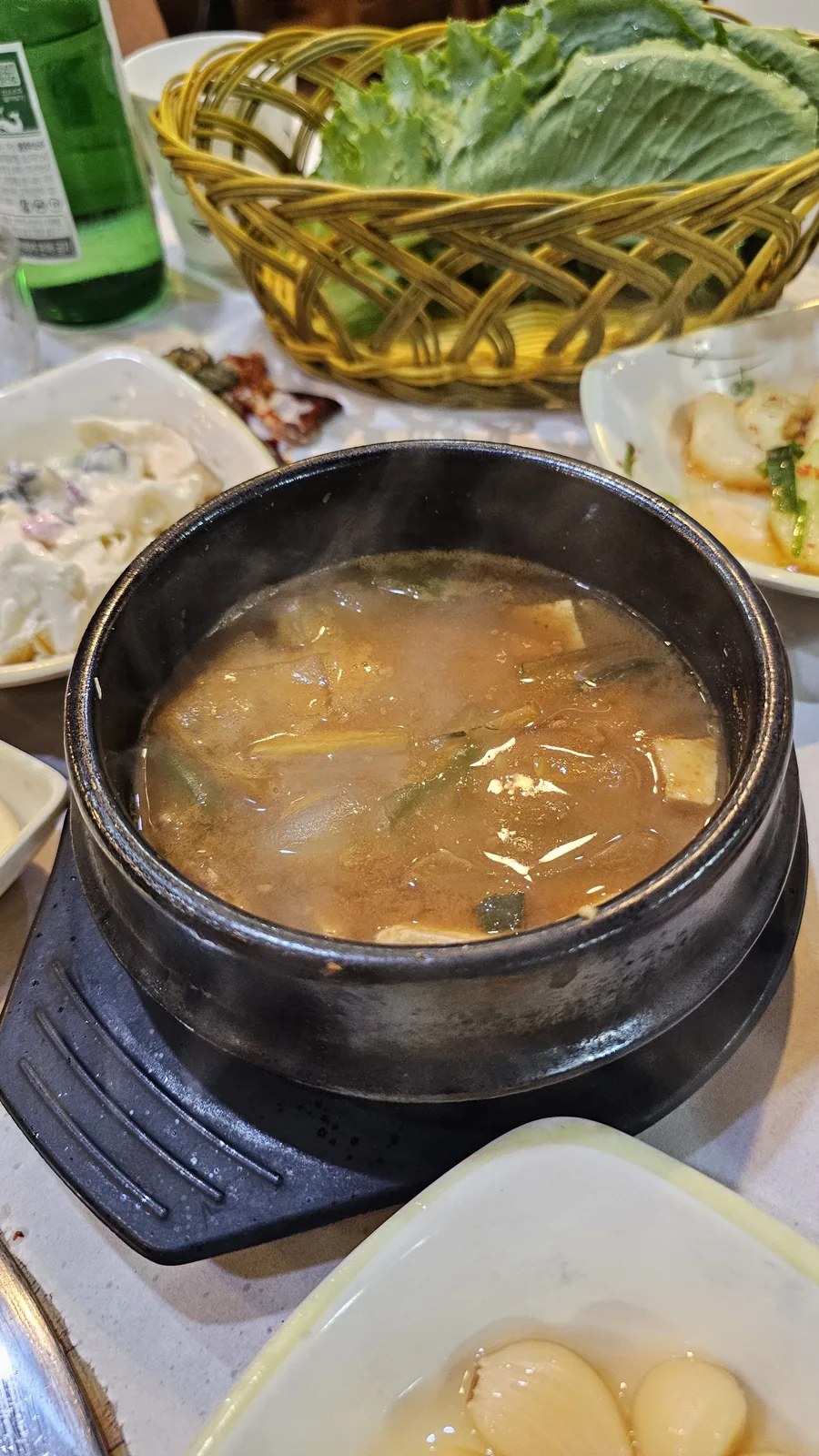 Doenjang jjigae in earthenware pot with tofu and vegetables at Haeoeum