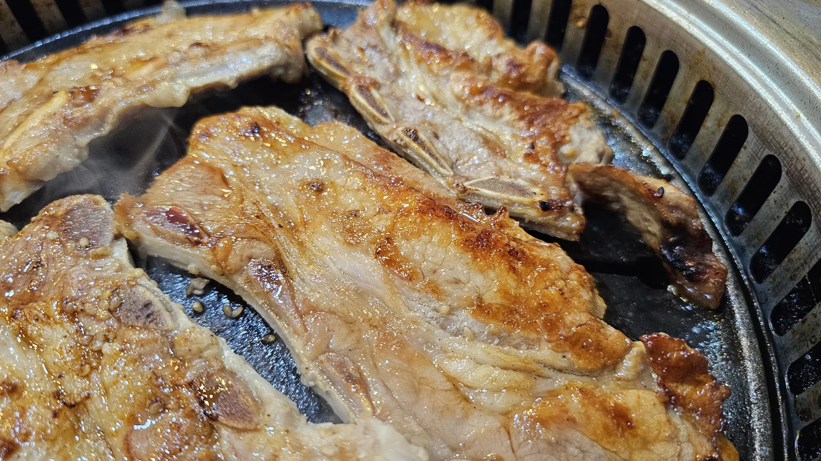 Fully cooked golden-brown yangnyeom dwaeji galbi on tabletop grill at Haeoeum Cheongyang