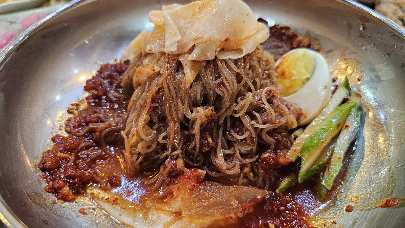 Bibim naengmyeon cold noodles with spicy sauce, soft-boiled egg, cucumber, and sliced pork at Haeoeum