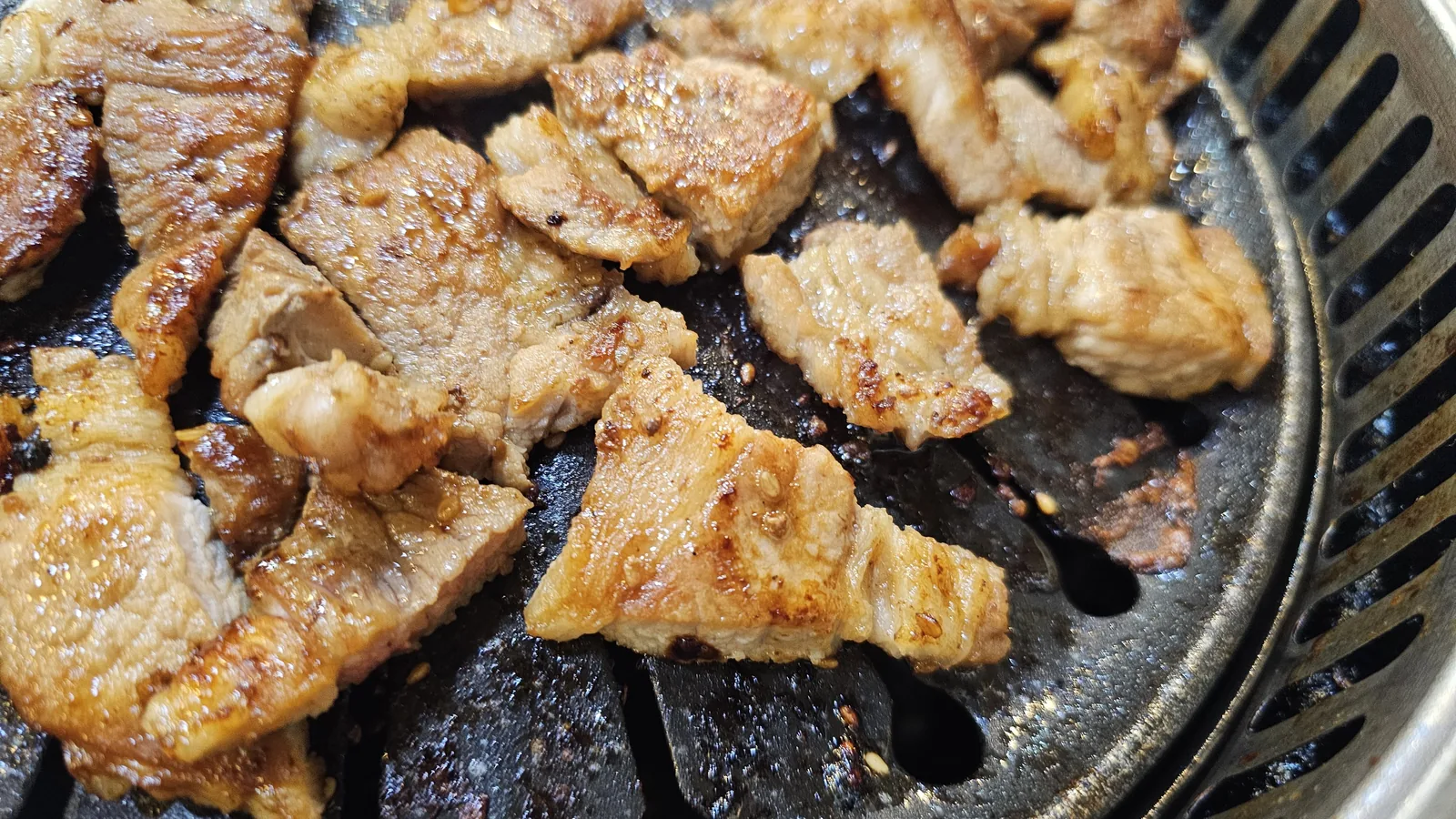 Scissors cutting grilled galbi into pieces on grill at Haeoeum in the final cooking stage
