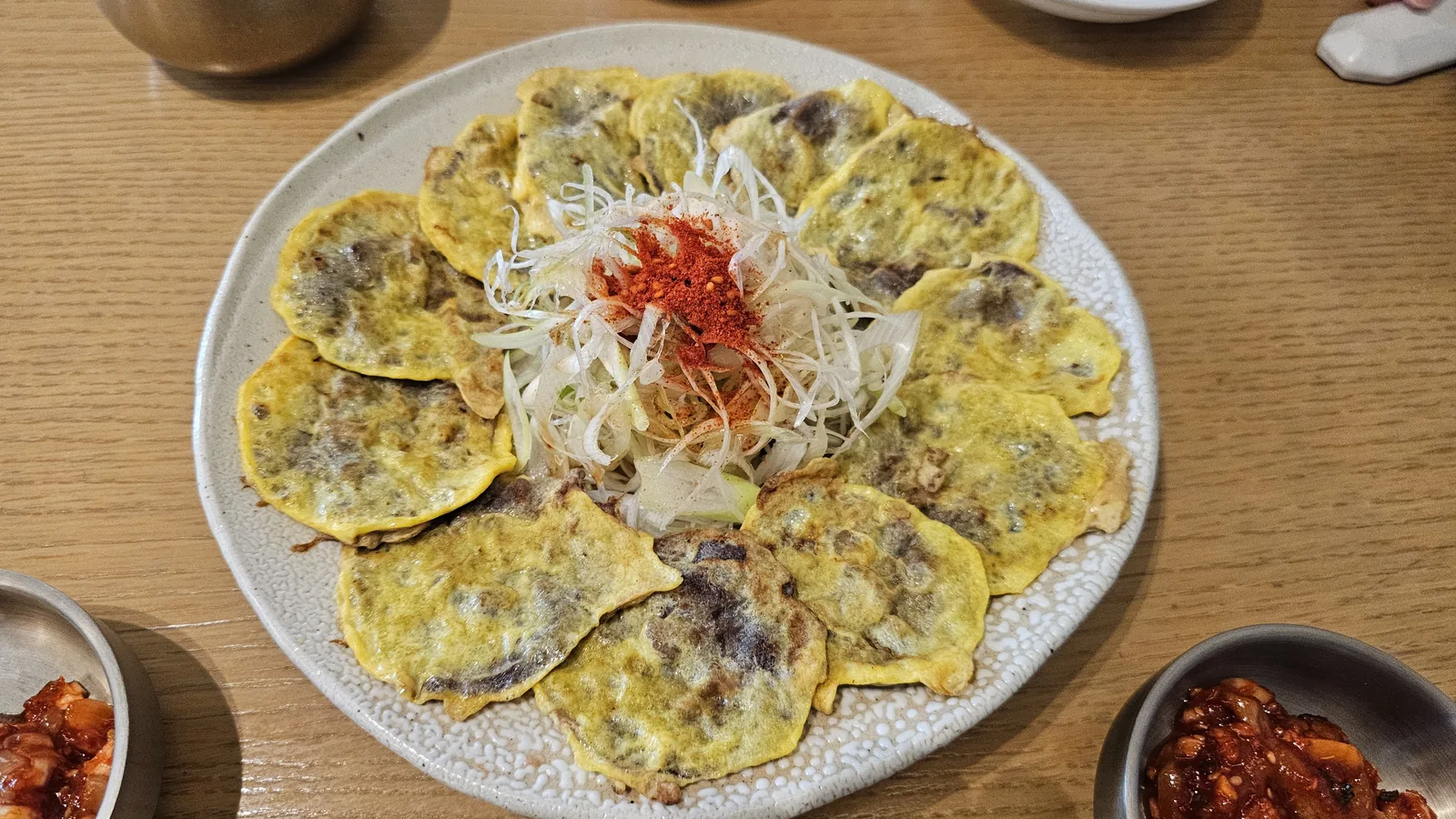 Banchan side dishes at Hanam-dong — kkakdugi and baechu kimchi on square plate, seasoned mushroom and jeotgal in stainless steel bowls