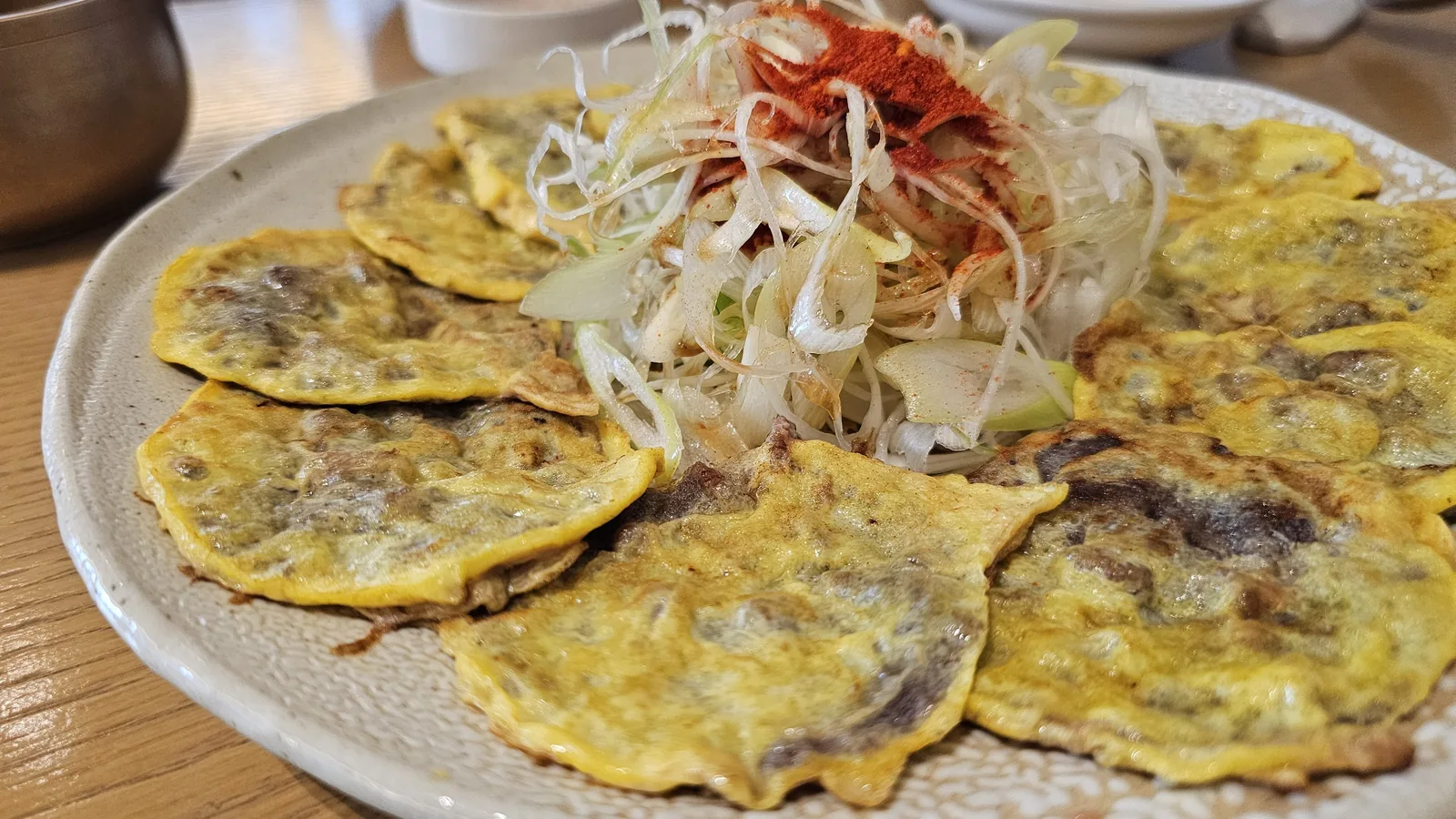 Close-up of hanwoo heifer beef jeon showing golden-brown crust and pan-fried texture with scallion topping at Hanam-dong Yeouido
