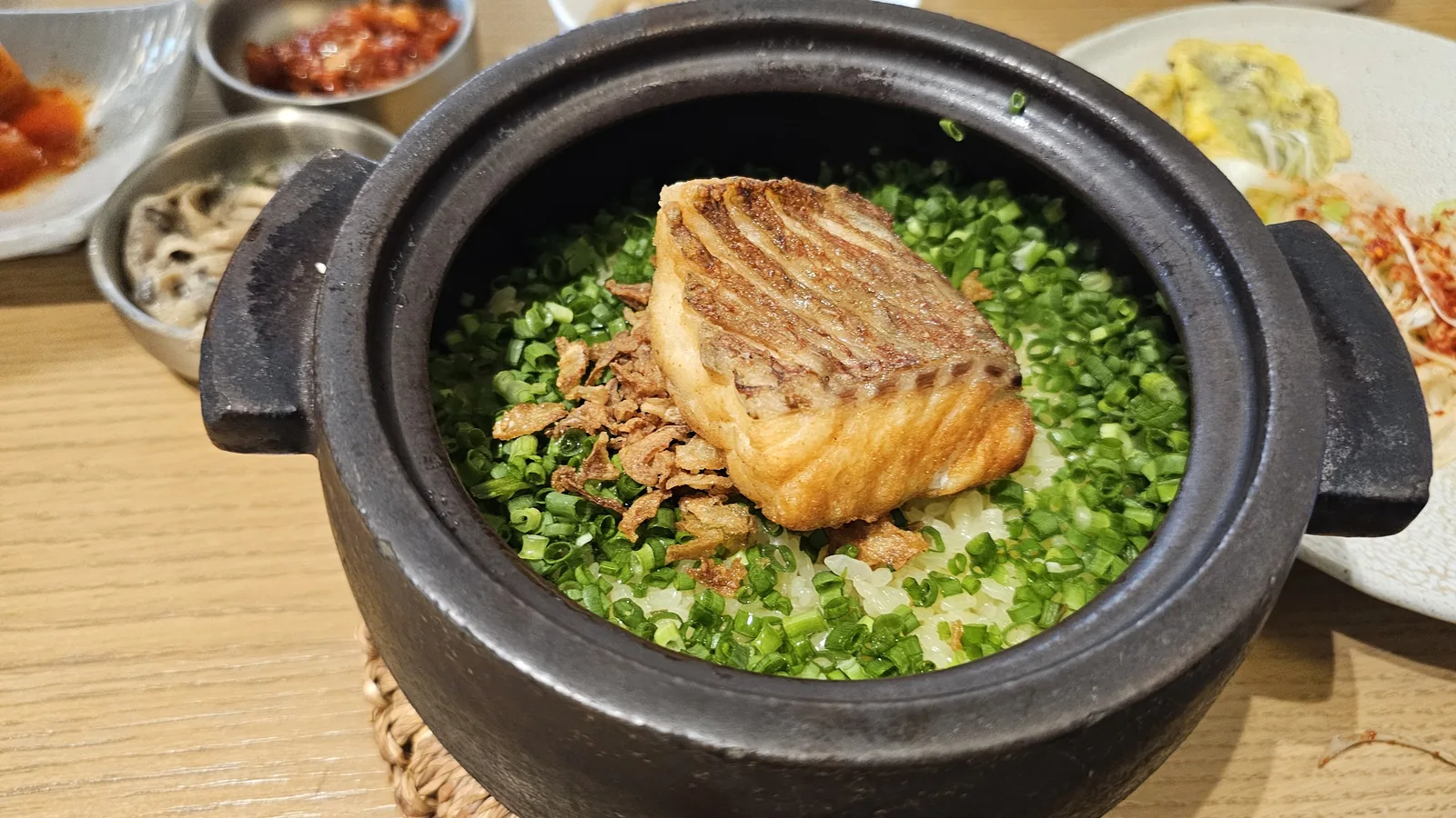Sea bream stone pot rice just after opening the lid — grilled fish on scallion rice in black iron pot at Hanam-dong