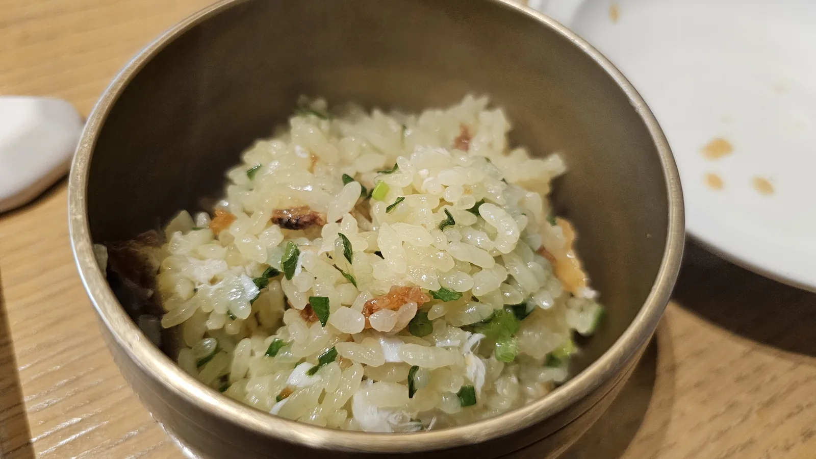 Individual bowl portion of sea bream stone pot rice with glossy rice, fish, and scallion mixed together at Hanam-dong