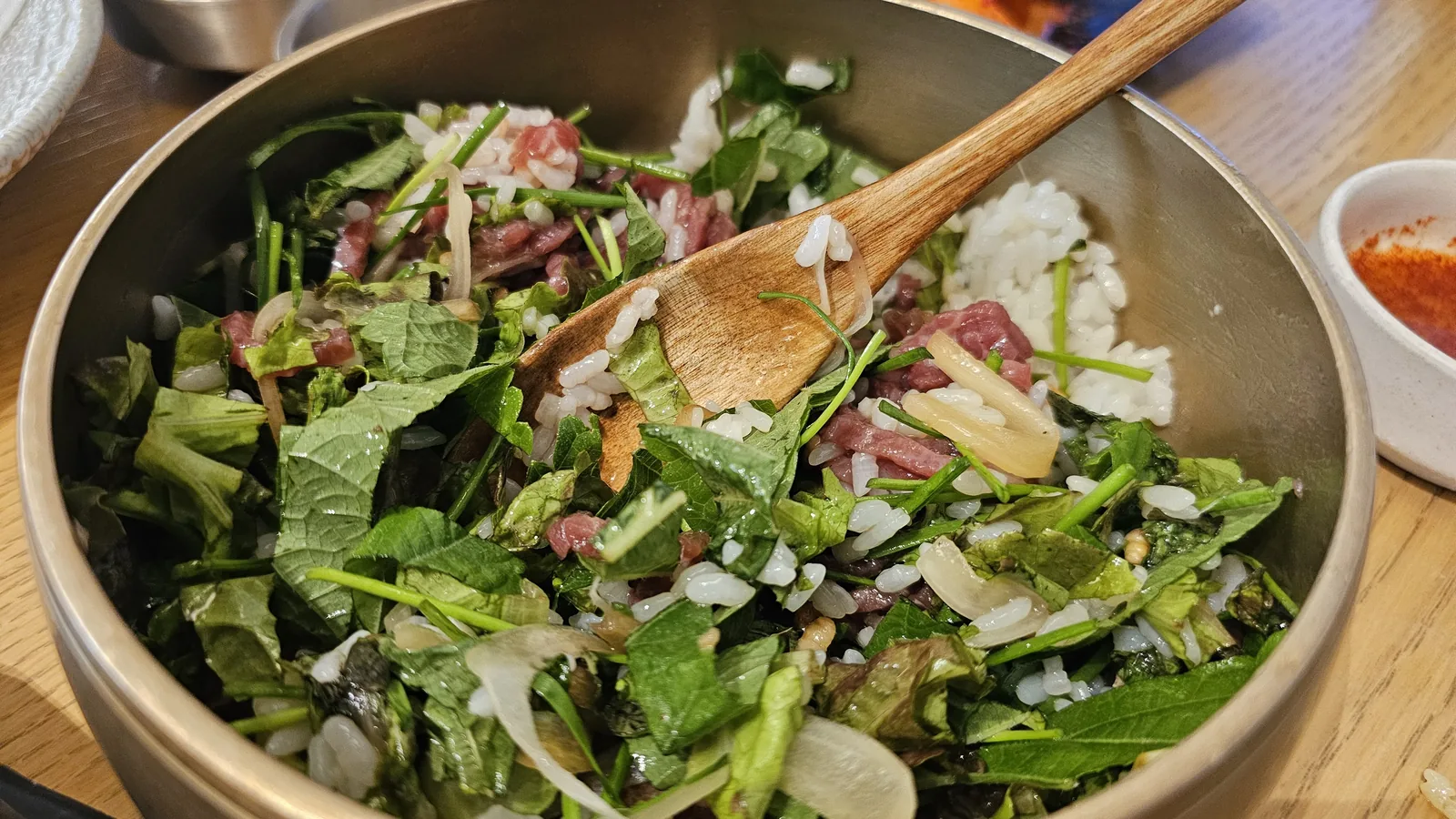 Mixing raw hanwoo yukhoe-style beef and vegetable bowl with wooden spatula at Hanam-dong Yeouido