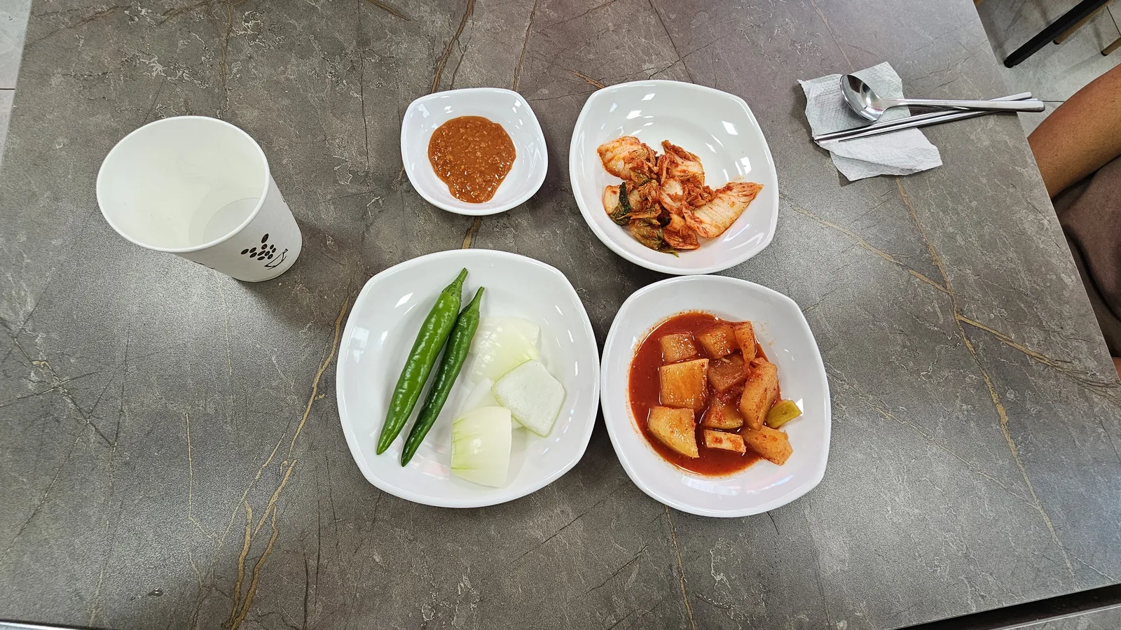 Traditional Korean side dish table set at Hwanggeum Dwaeji Gukbap — salted shrimp, kkakdugi, cheongyang peppers, onion and kimchi