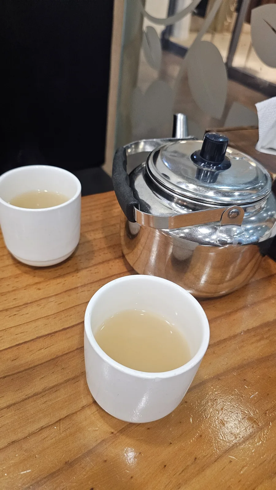 イルホミョノクで無料提供されるステンレスのやかんと白い湯飲みに入ったユクス(육수)牛骨スープ