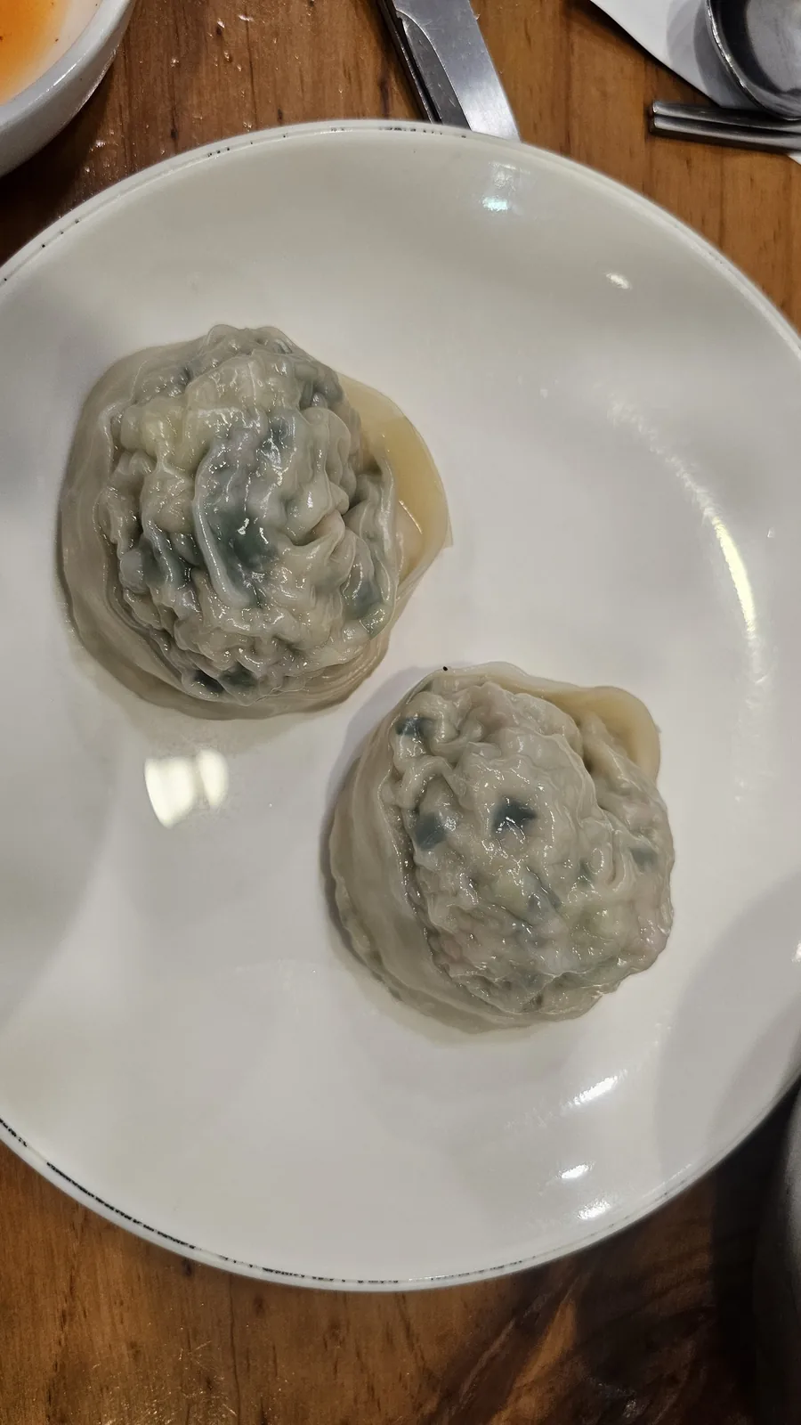 イルホミョノクの白い皿に盛られた半透明の皮の大きな韓国式ワンマンドゥ蒸し餃子2個