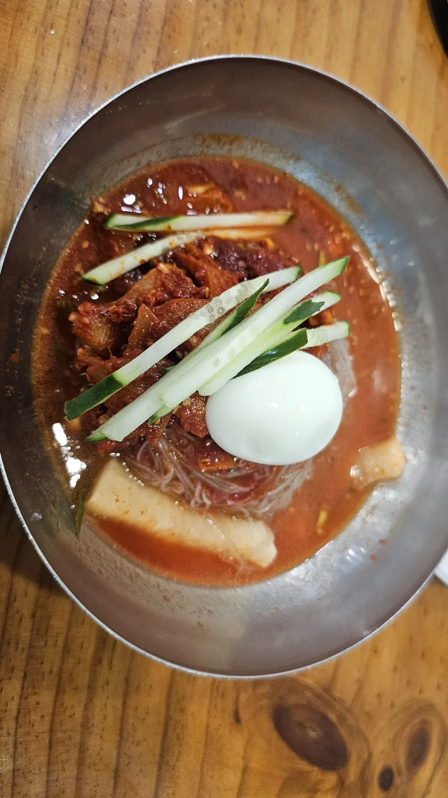 イルホミョノク汝矣島のフェネンミョン。辛い赤いタレにピョニュク牛肉、キュウリ、大根、半熟卵を添えた冷麺
