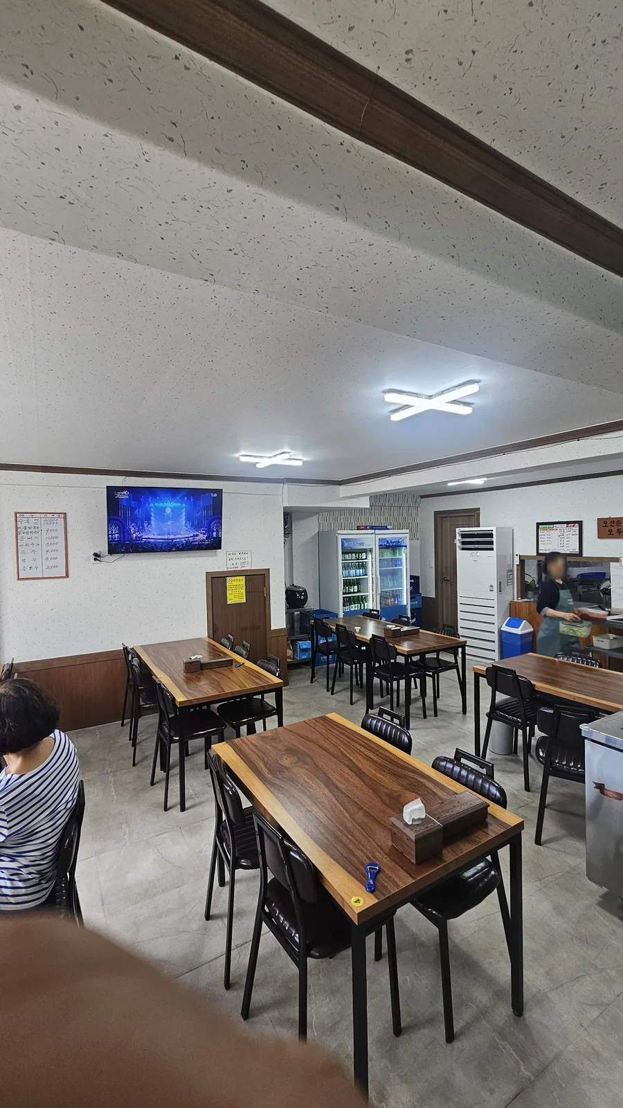 Interior of Jangsu Makguksu in Cheongyang with wooden tables, black chairs, and LED wall decorations