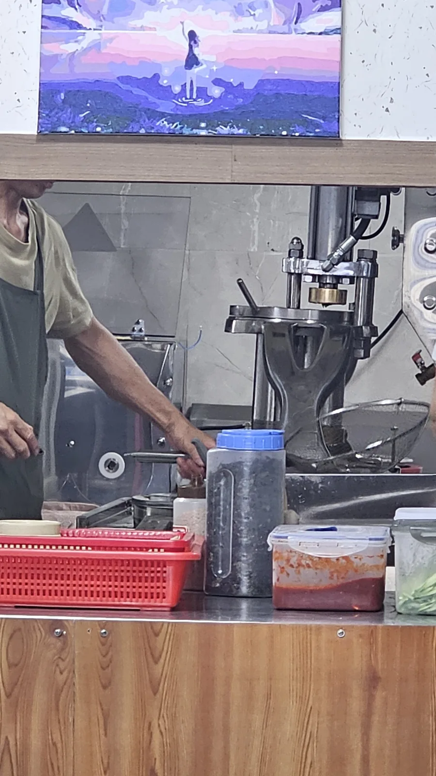 Kitchen staff at Jangsu Makguksu operating a fresh noodle press machine to make buckwheat noodles in-house