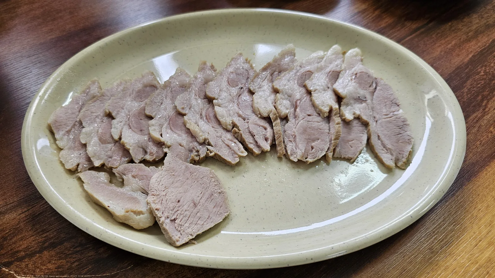 Thinly sliced subyuk boiled pork on an oval plate at Jangsu Makguksu in Cheongyang