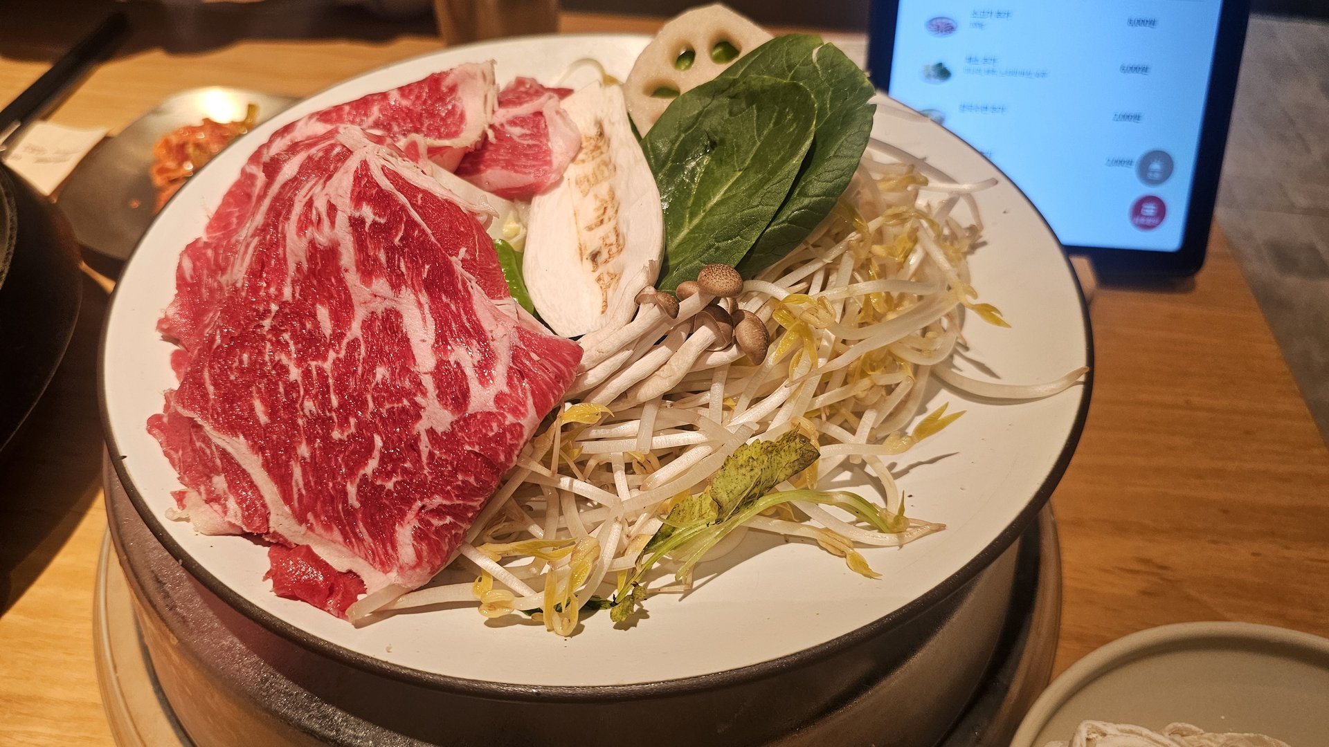Shabu shabu ingredient plate at Jeil Myeonso with marbled beef slices, mushrooms, bean sprouts, bok choy, and lotus root