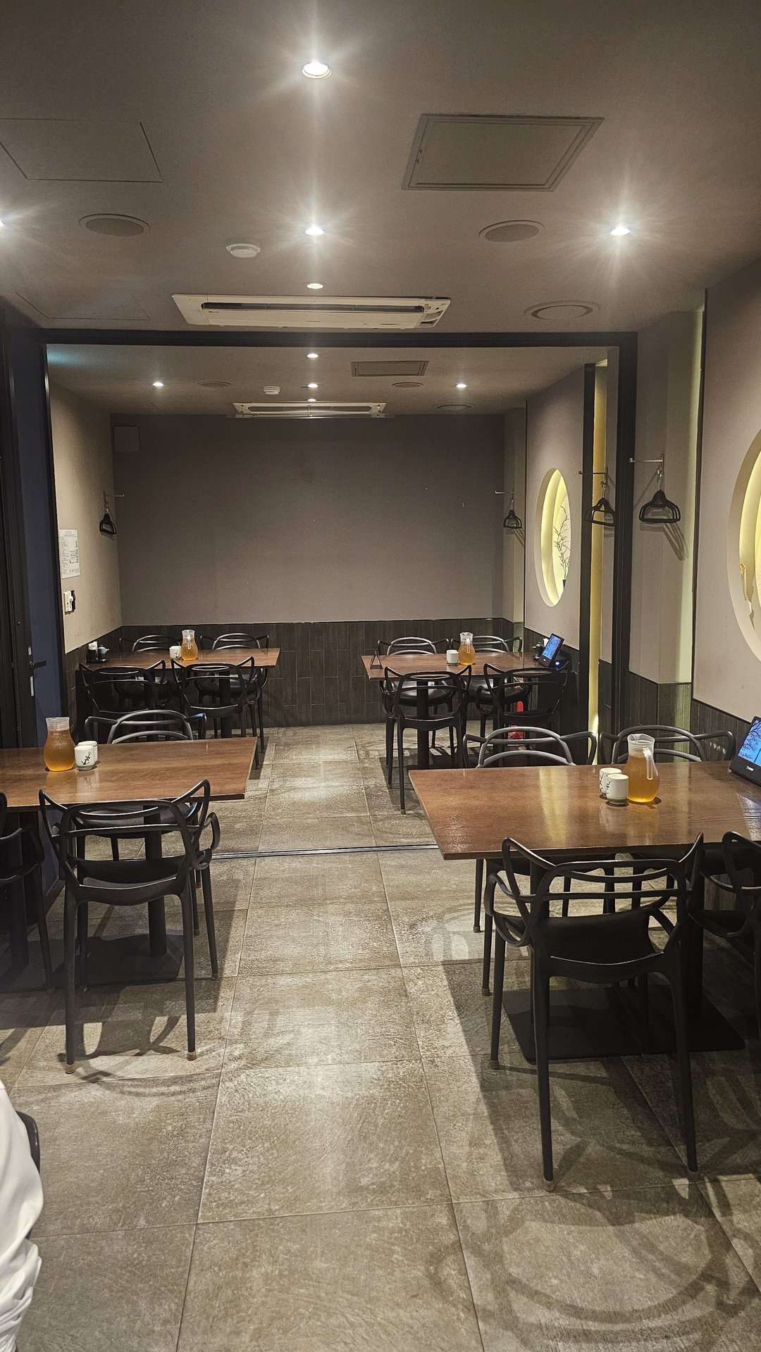 Interior of Jingawa Yeouido with wooden tables and black iron chairs under warm lighting