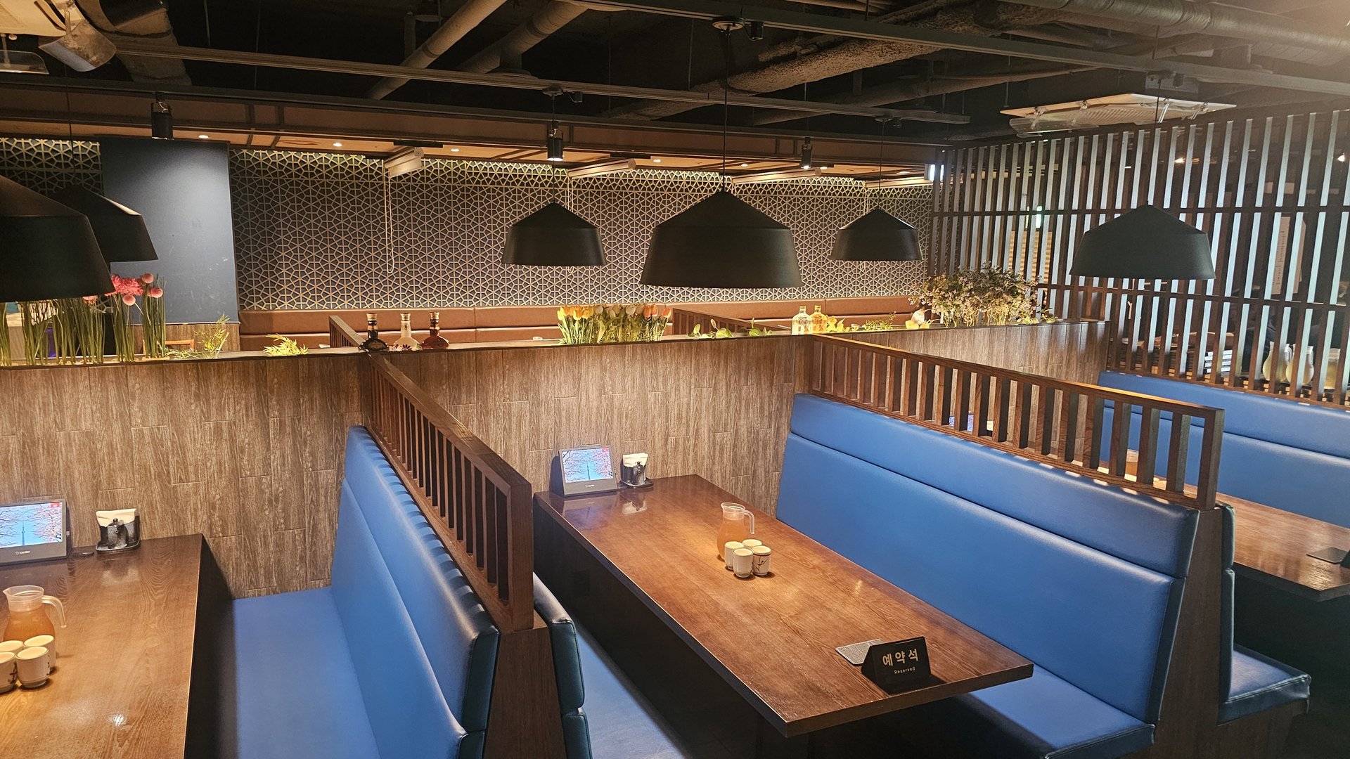 Upper seating area at Jingawa Yeouido featuring blue fabric booth sofas and wooden partition dividers