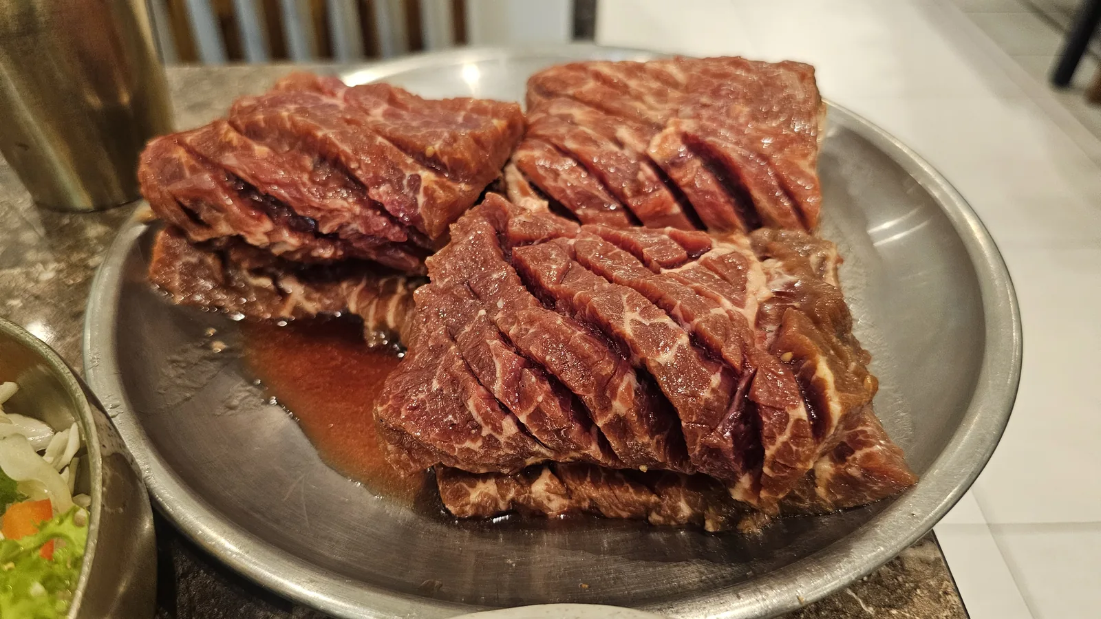 Four bone-in raw beef short ribs (saeng galbi) on a plate before grilling at Jogane Galbi Mokdong