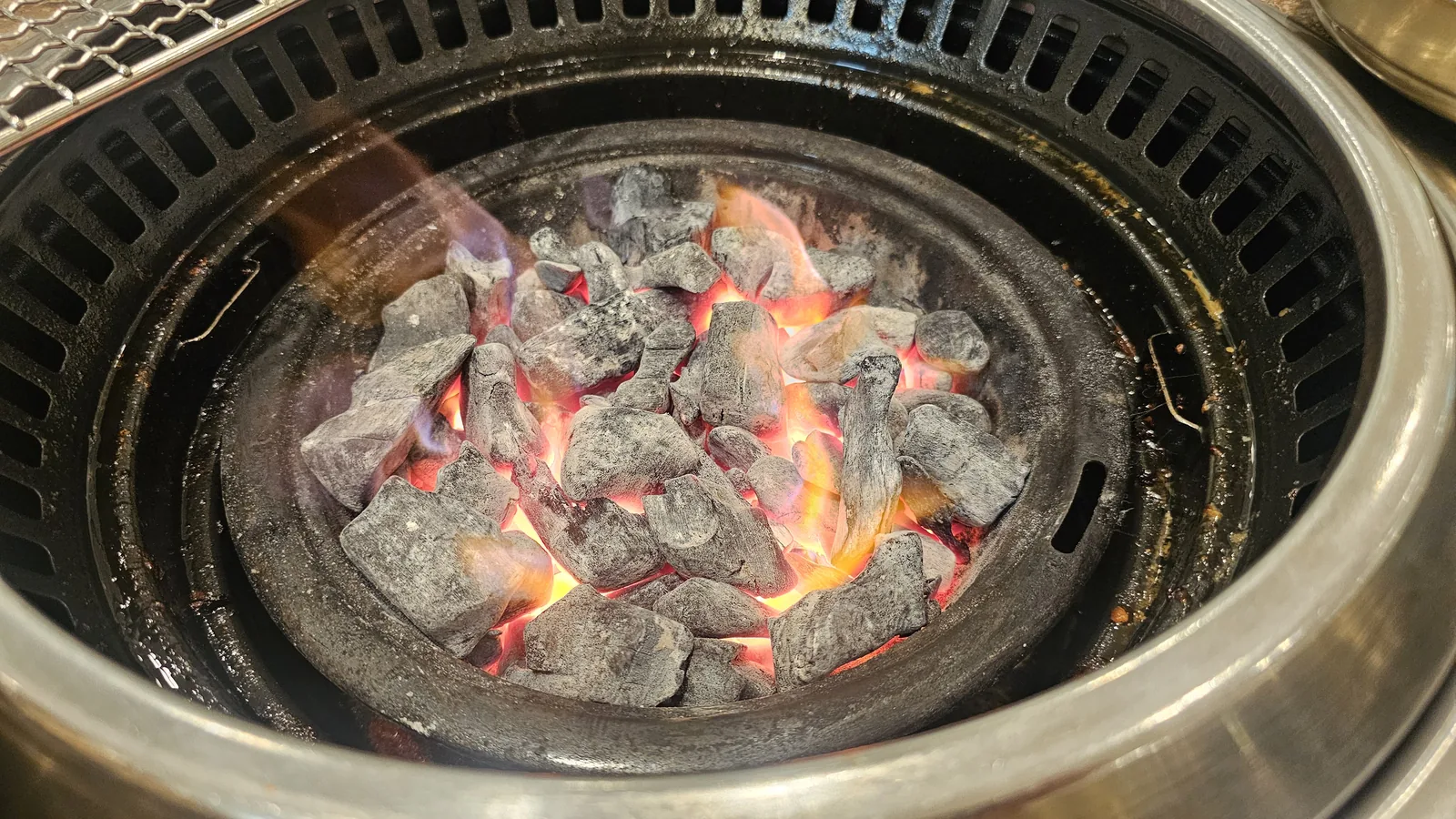 Charcoal fire blazing in the round cast-iron brazier at Jogane Galbi Mokdong