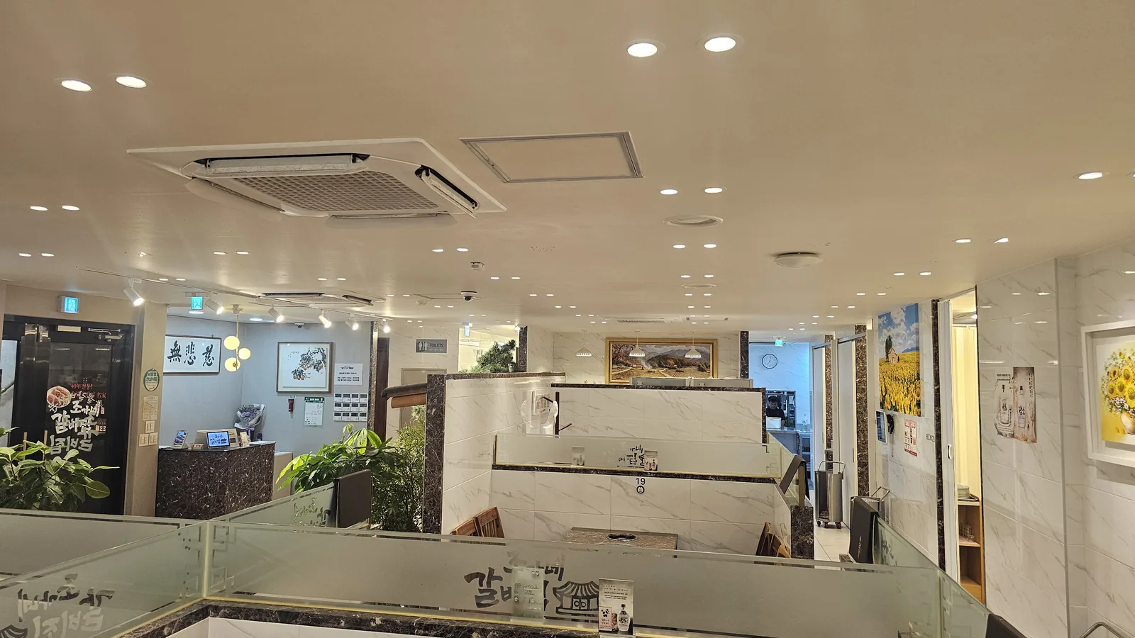 Interior of Jogane Galbi Mokdong showing booth seating with dividers, front counter, and decorative wall art