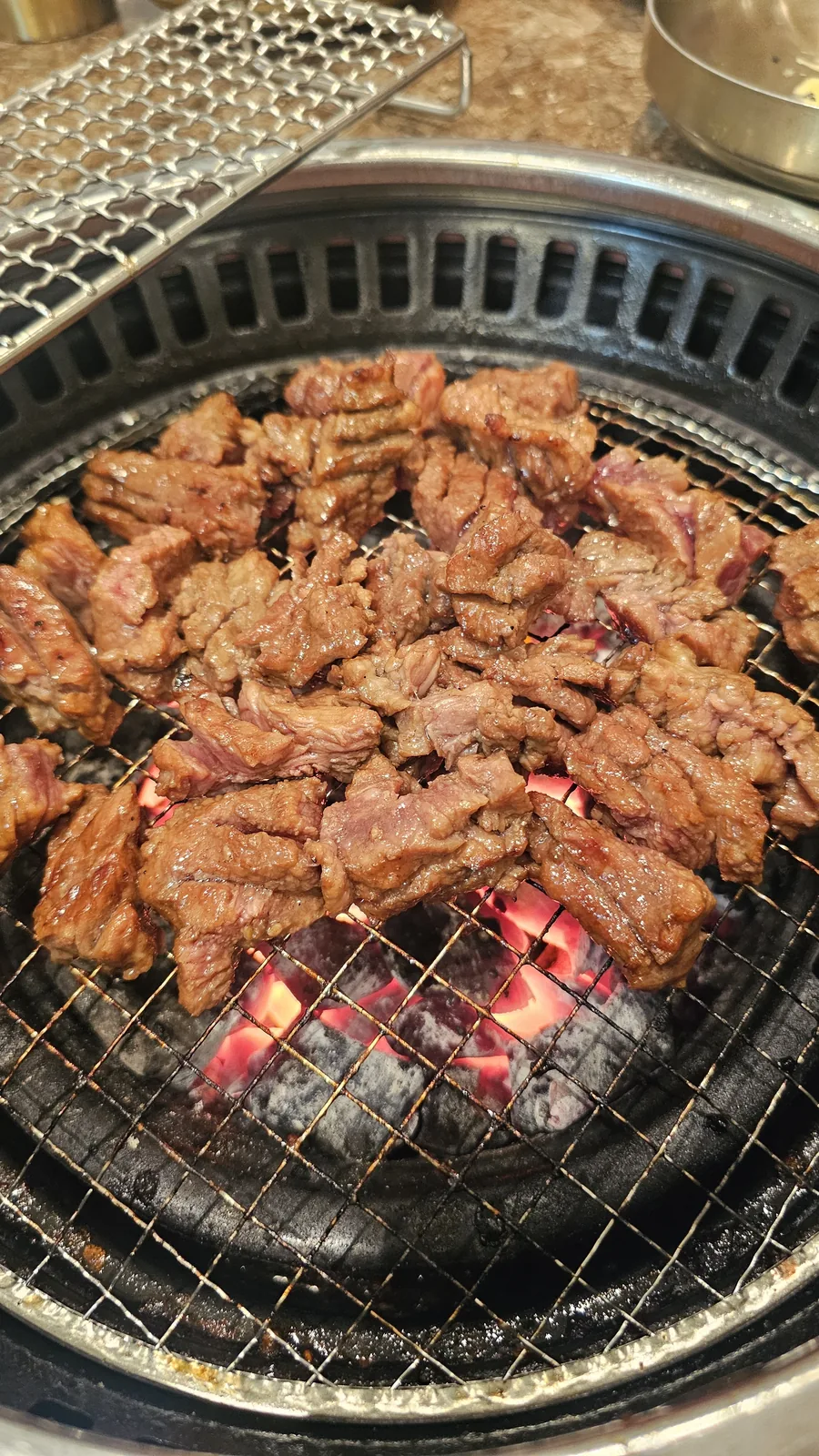 Fully cooked beef galbi pieces on charcoal grill at Jogane Galbi, ready to eat