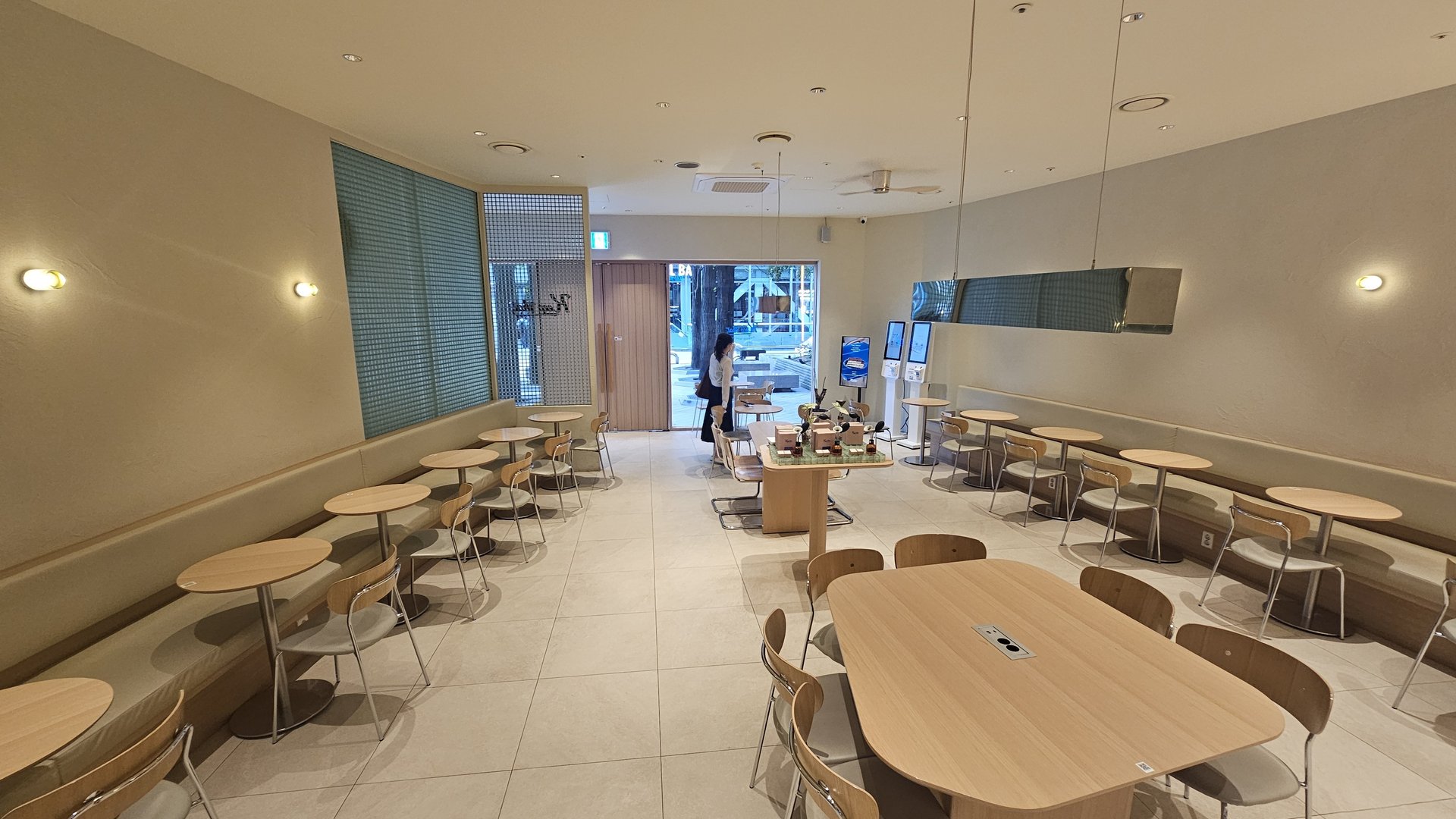 Spacious and clean interior of Keep That Coffee Yeouido with round and oval wooden tables arranged in rows