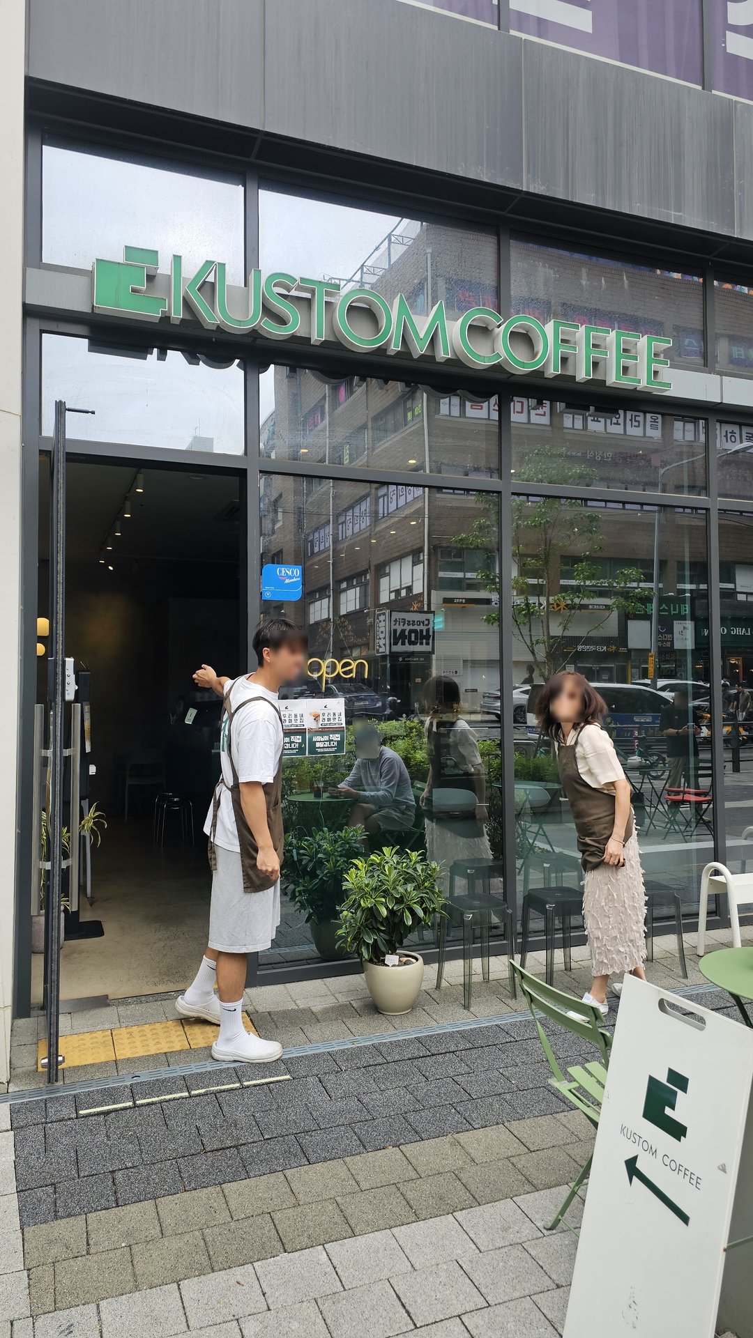 Kustom Coffee Yeouido exterior with green logo on glass facade and customers at entrance