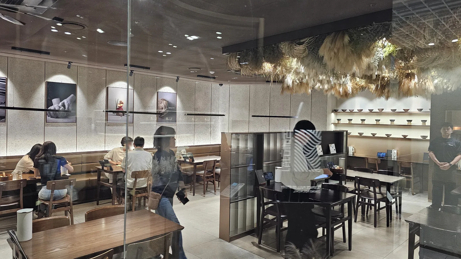 Interior of Meomil Danpyeon through glass wall showing dried flower ceiling installation and brass bowl display case
