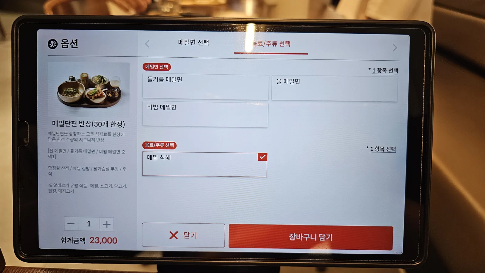 Tablet ordering screen at Meomil Danpyeon with 23000 KRW bansang set and perilla oil noodle option selected