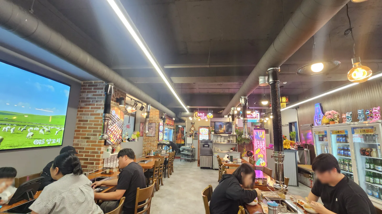 Busy dinner scene inside Miyeon Yangkkochi Maratang Cheongyang with brick walls, neon signs, and TV screen