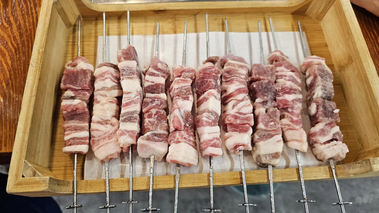 Top-down view of raw lamb skewers arranged on wooden serving tray at Miyeon Yangkkochi Cheongyang