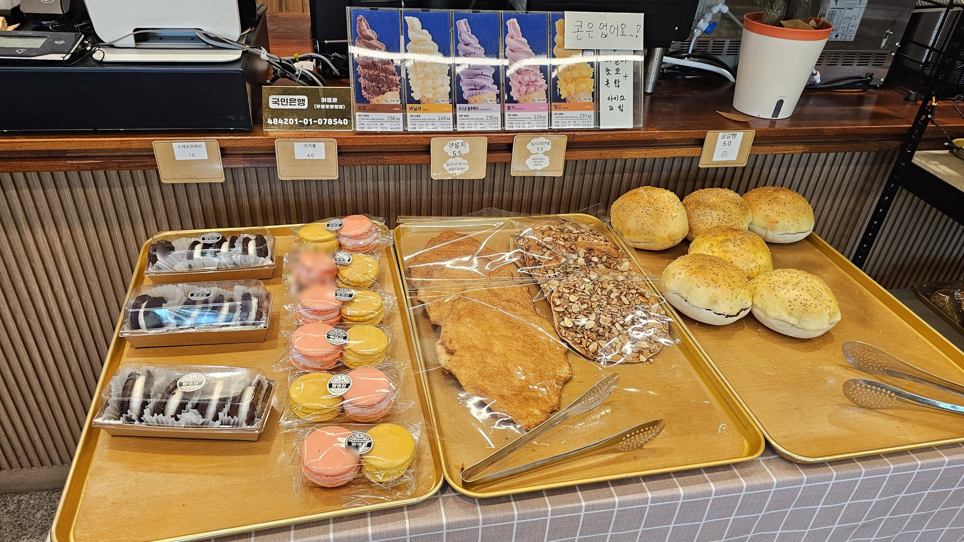 Tray display with macarons, chocolate bars, almond croissant bread, and ice cream menu photo at Mochang-po Bakery