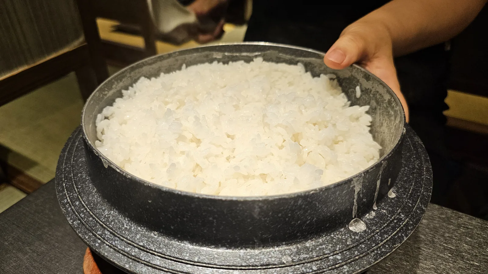汝矣島ムッキ ボリグルビのテーブルにスタッフが石鍋(돌솥、ドルソッ)の白ご飯を運んでいる様子